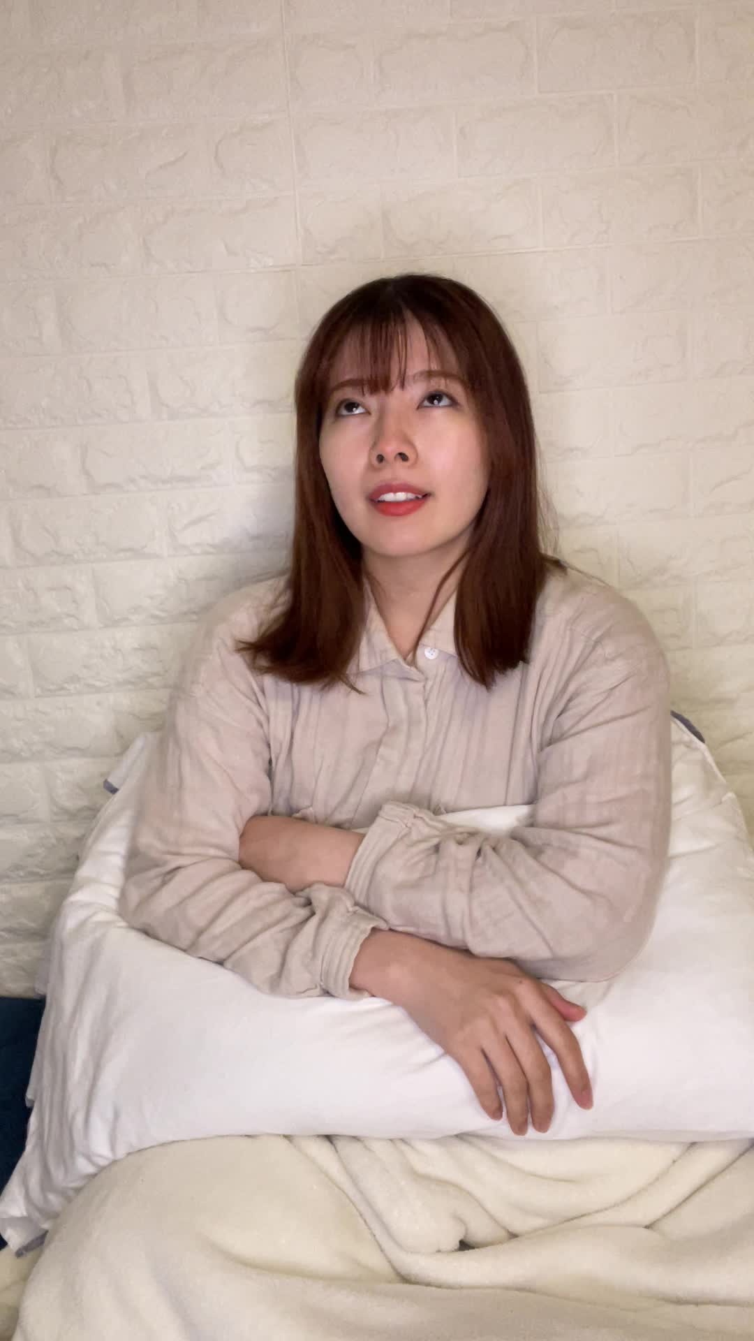 ベッドでクッションを抱え、「このドリンクを続けたら変化があるかな？」と未来を想像する表情