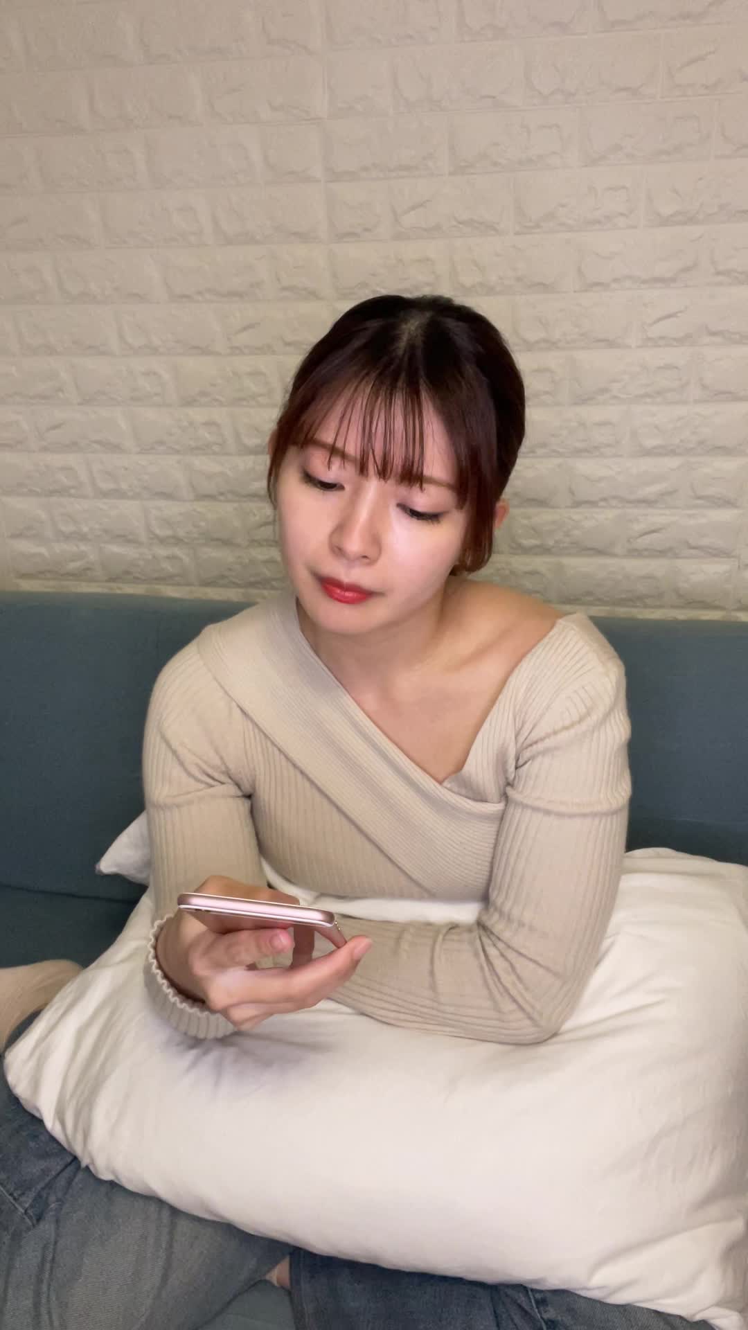 ソファで膝を曲げながら、「疲れた体に何が必要か考えて健康ドリンクを検討する」様子