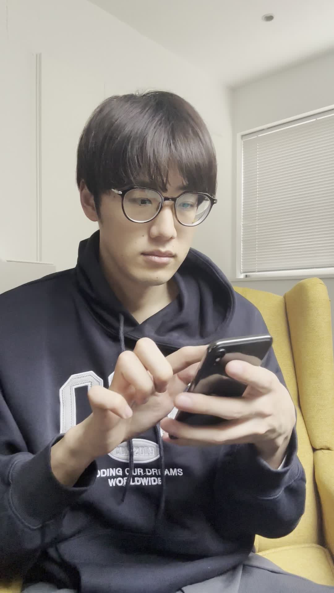 椅子に腰掛け、スマホを置いて「早く観たい！」と小さくガッツポーズをする仕草