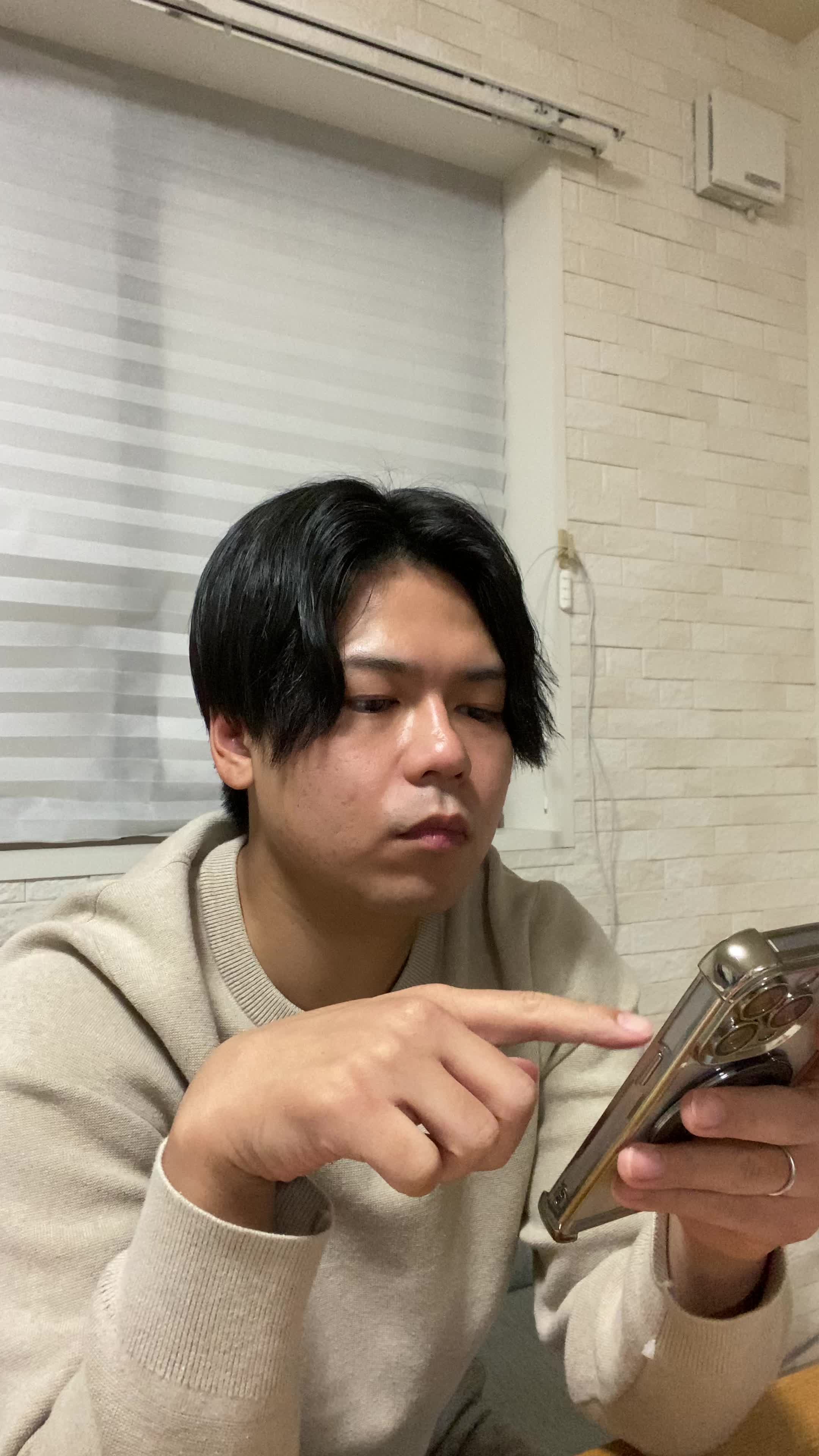 テーブルでスマホに検索結果をスクロールしながら、「どの矯正方法がいいのかな？」と考える仕草