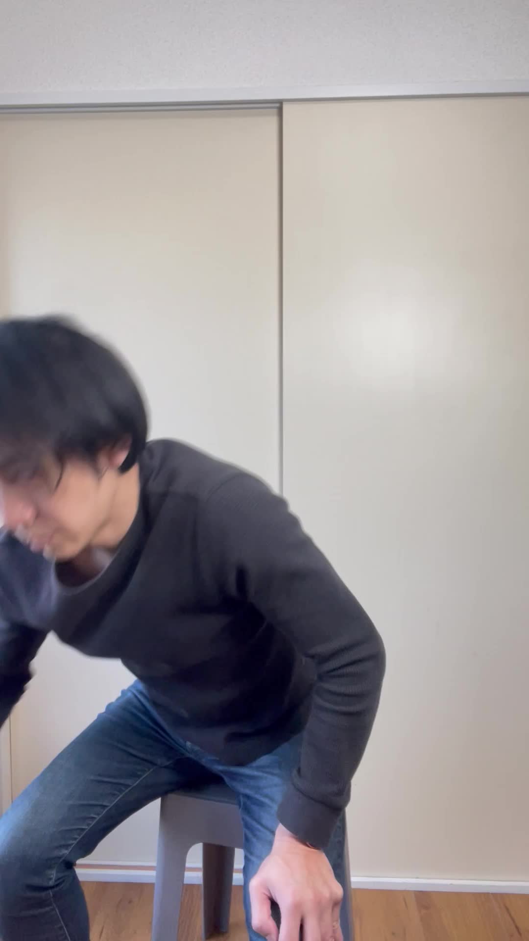 椅子に座り、お腹を軽く押さえながら「ずっと痛みが続いている…」と苦しそうな表情