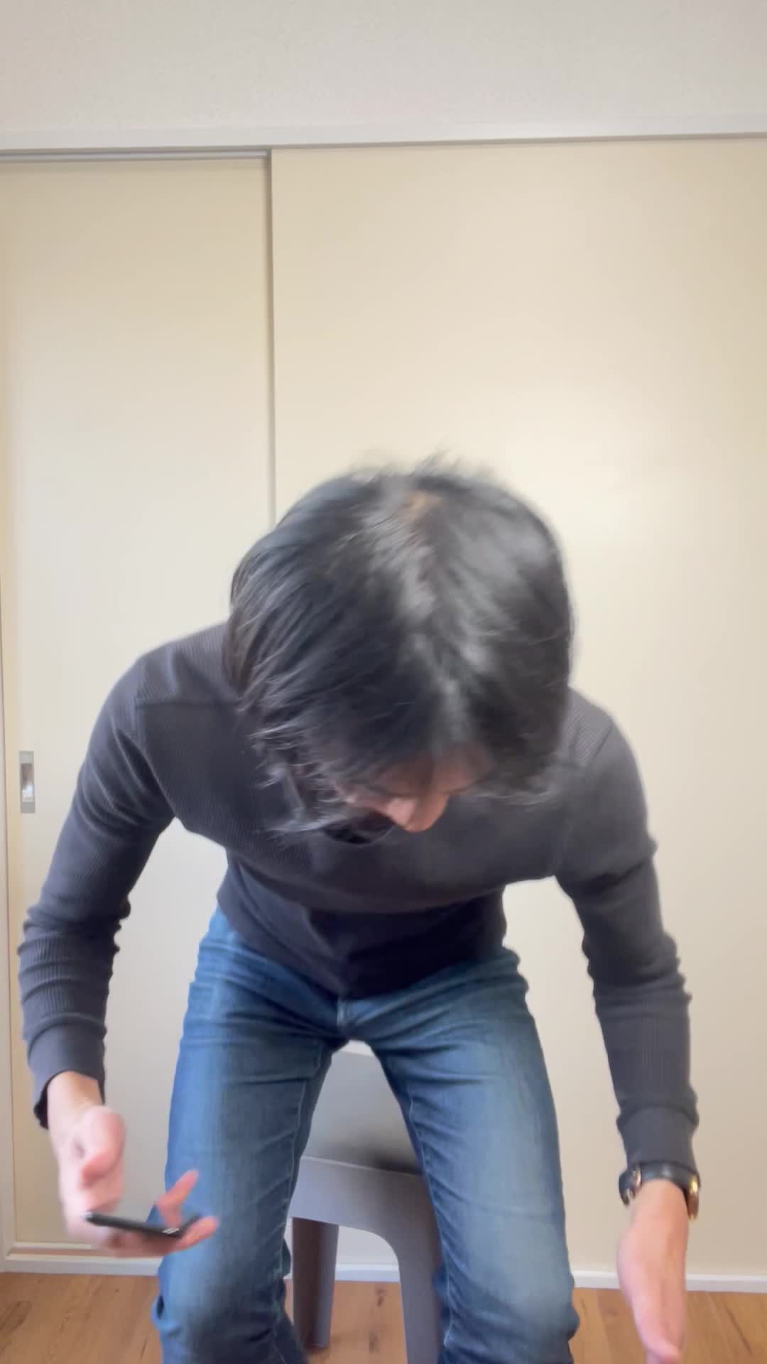 椅子に腰掛け、「腸の調子を整えるための対策を必死に調べる」動作