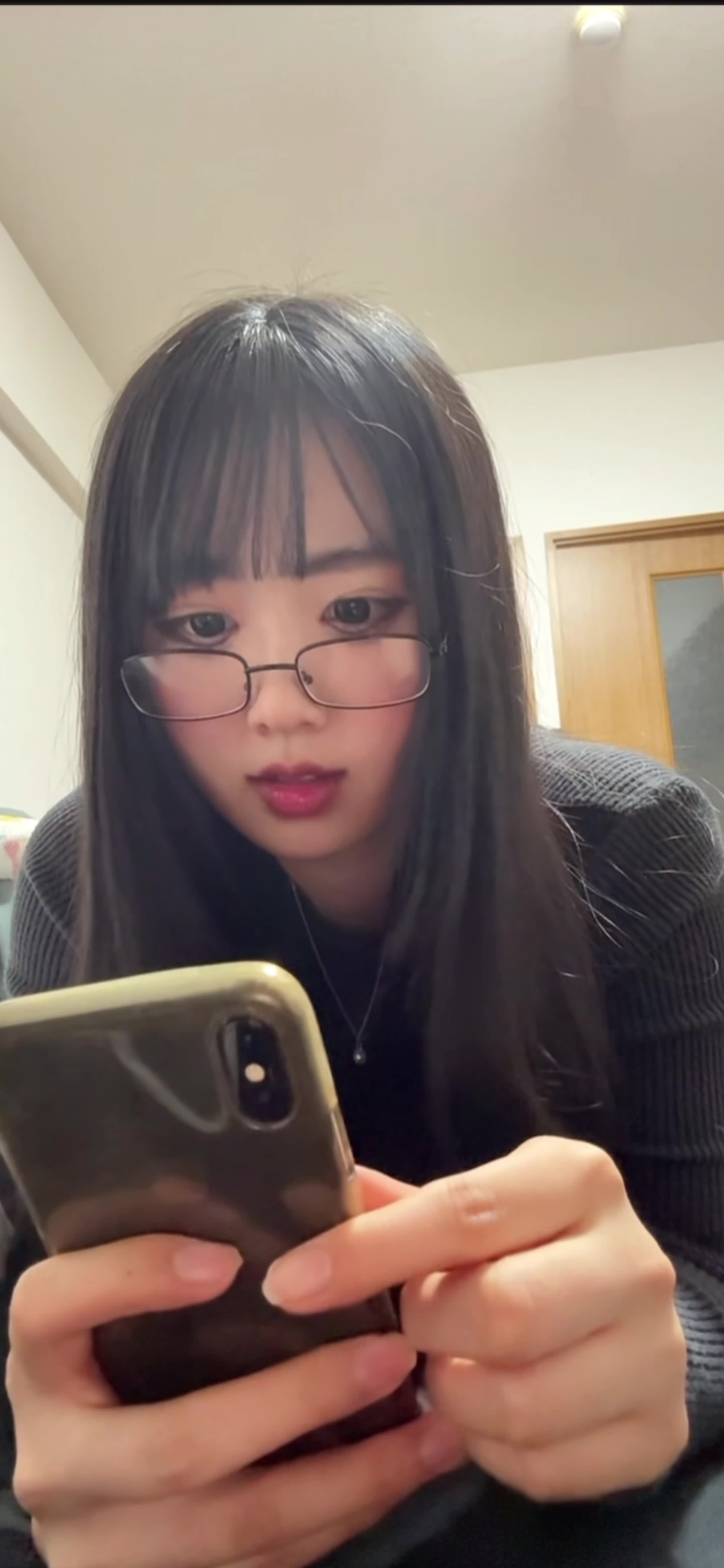 ベッドで横になり、スマホを見ながら「本当に稼げるの？」と疑うような顔