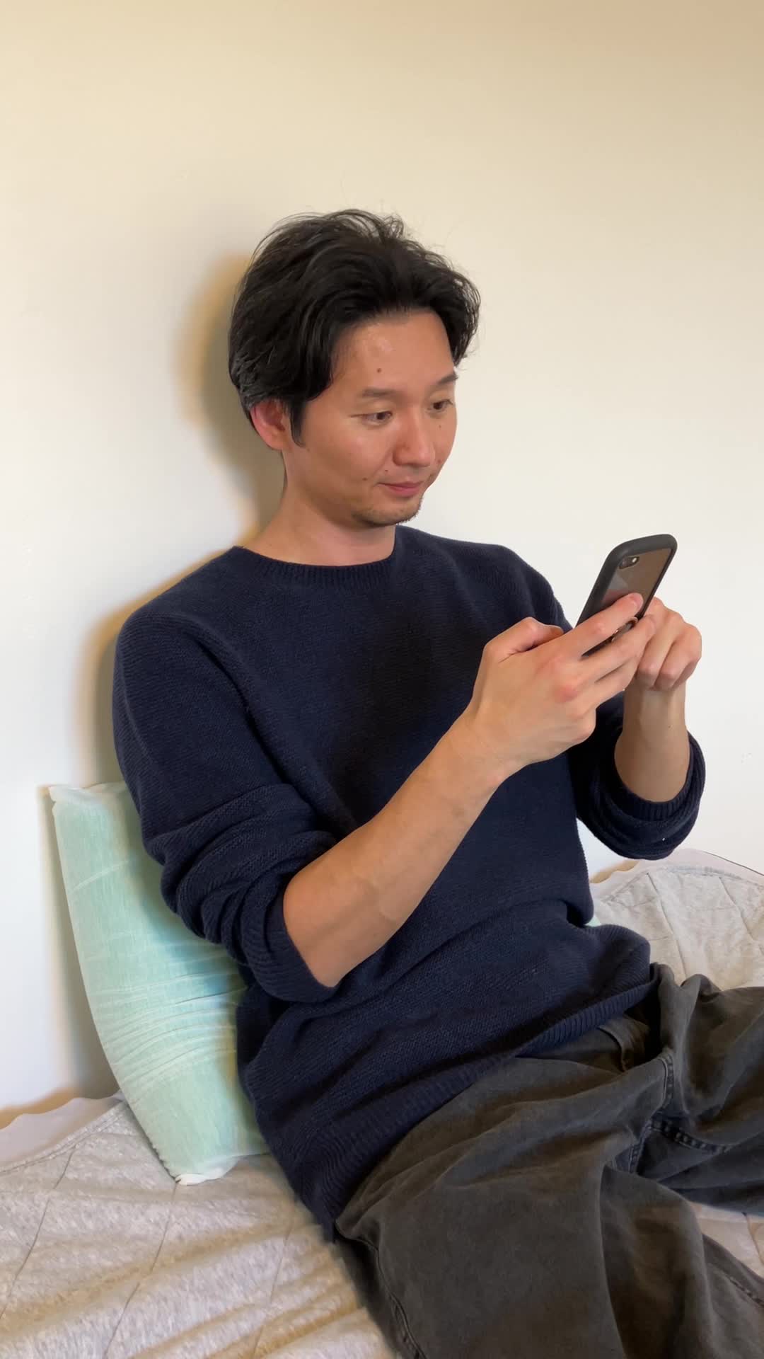 ベッドで脚を伸ばし、スマホの画面を見ながら「契約前にチェックするポイント」を確認する表情