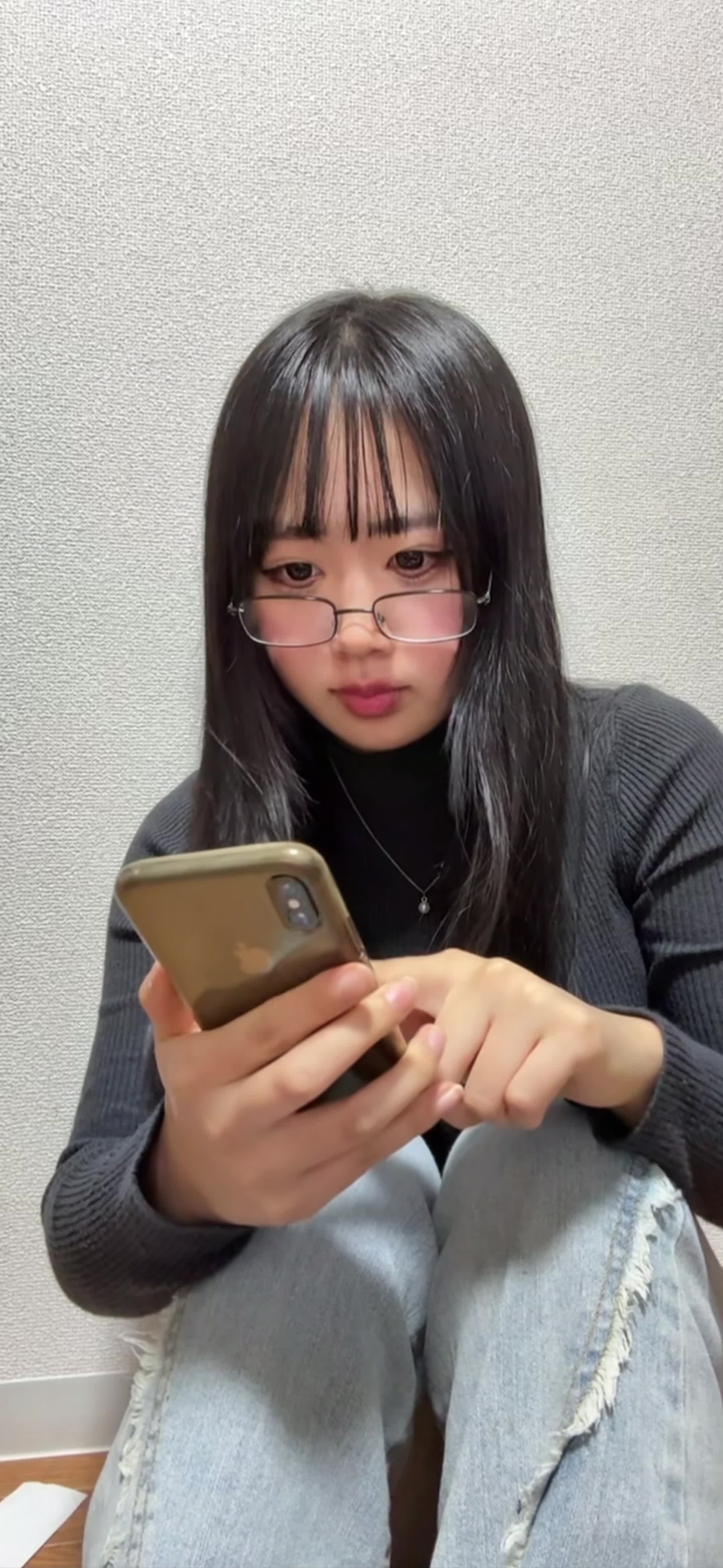 床に座り込み、スマホで「保険の口コミ」を見ながら少し安心した表情を浮かべる