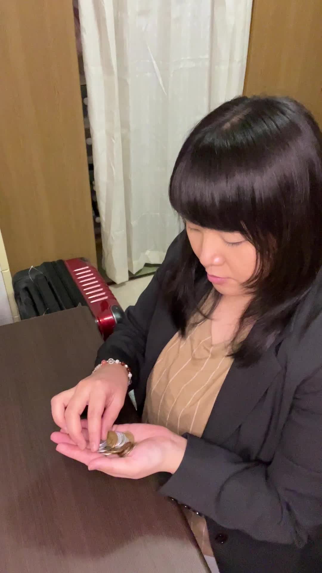 椅子に腰掛け、コインを指先で丁寧に並べていく動作