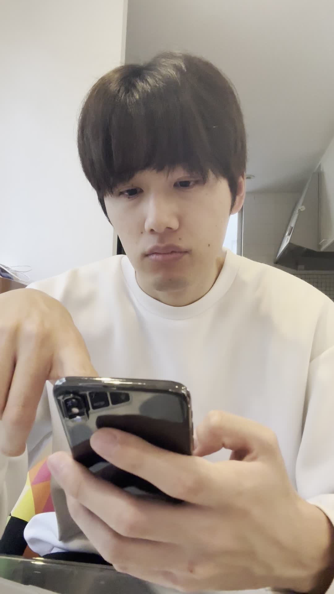 テーブルでスマホに検索結果をスクロールしながら、「どの矯正方法がいいのかな？」と考える仕草