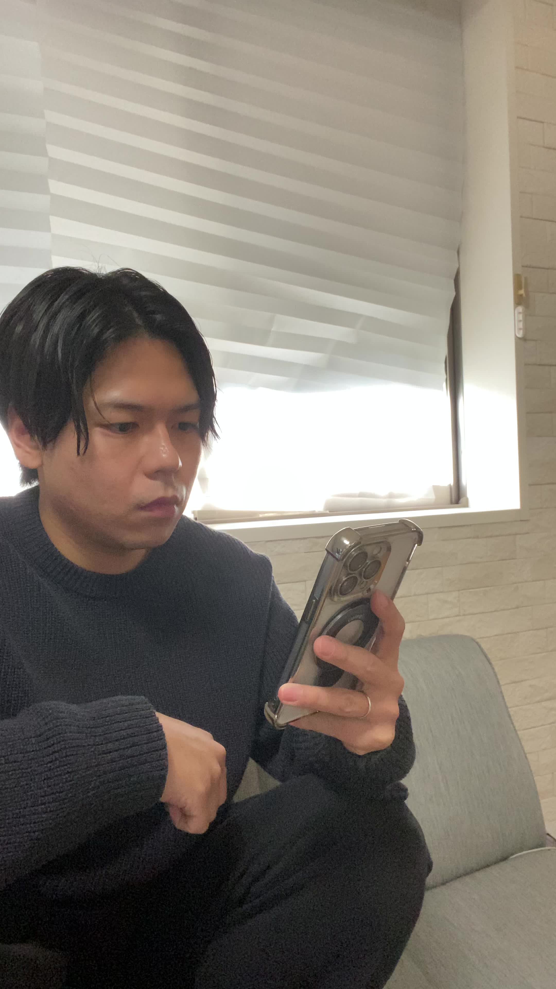 ソファでクッションを抱え、スマホの画面を見て「これがタイムセール価格？」と驚く様子