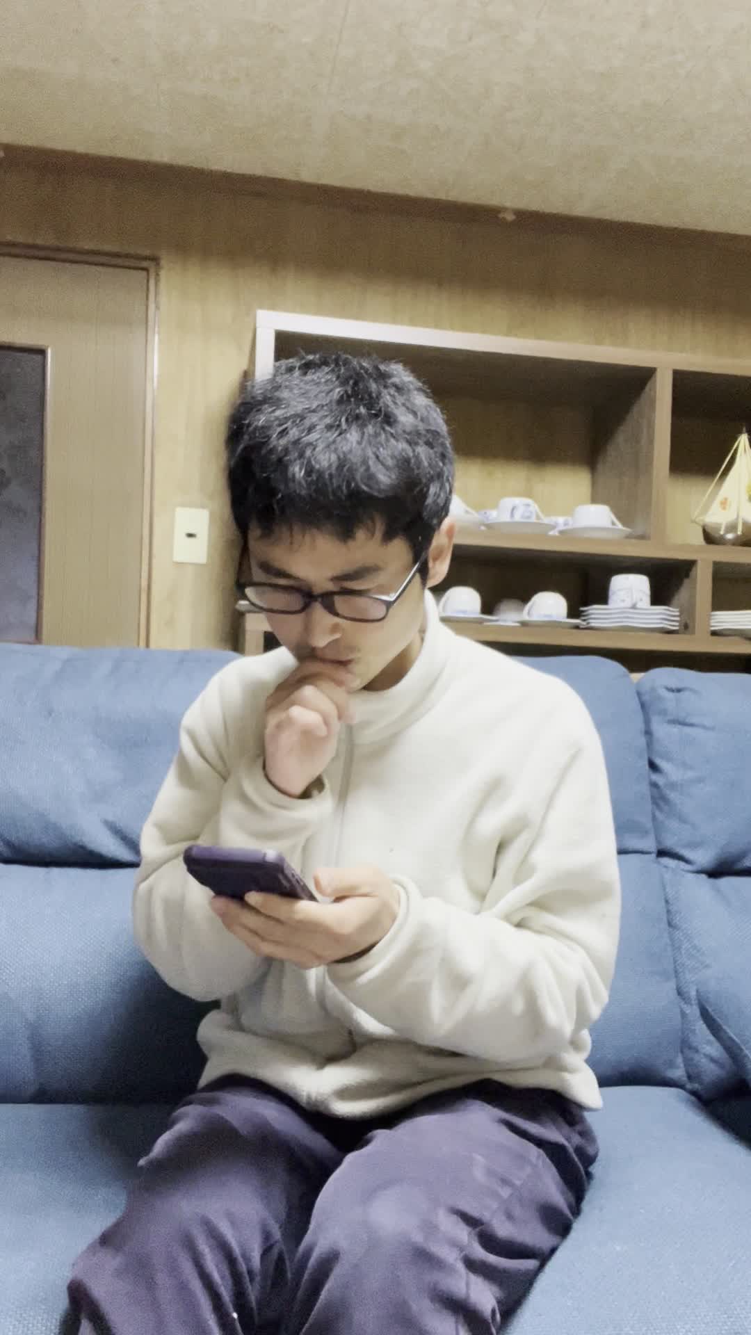 ソファでスマホを見ながら、「腸活の方法を見つけて試したいけど迷う」表情