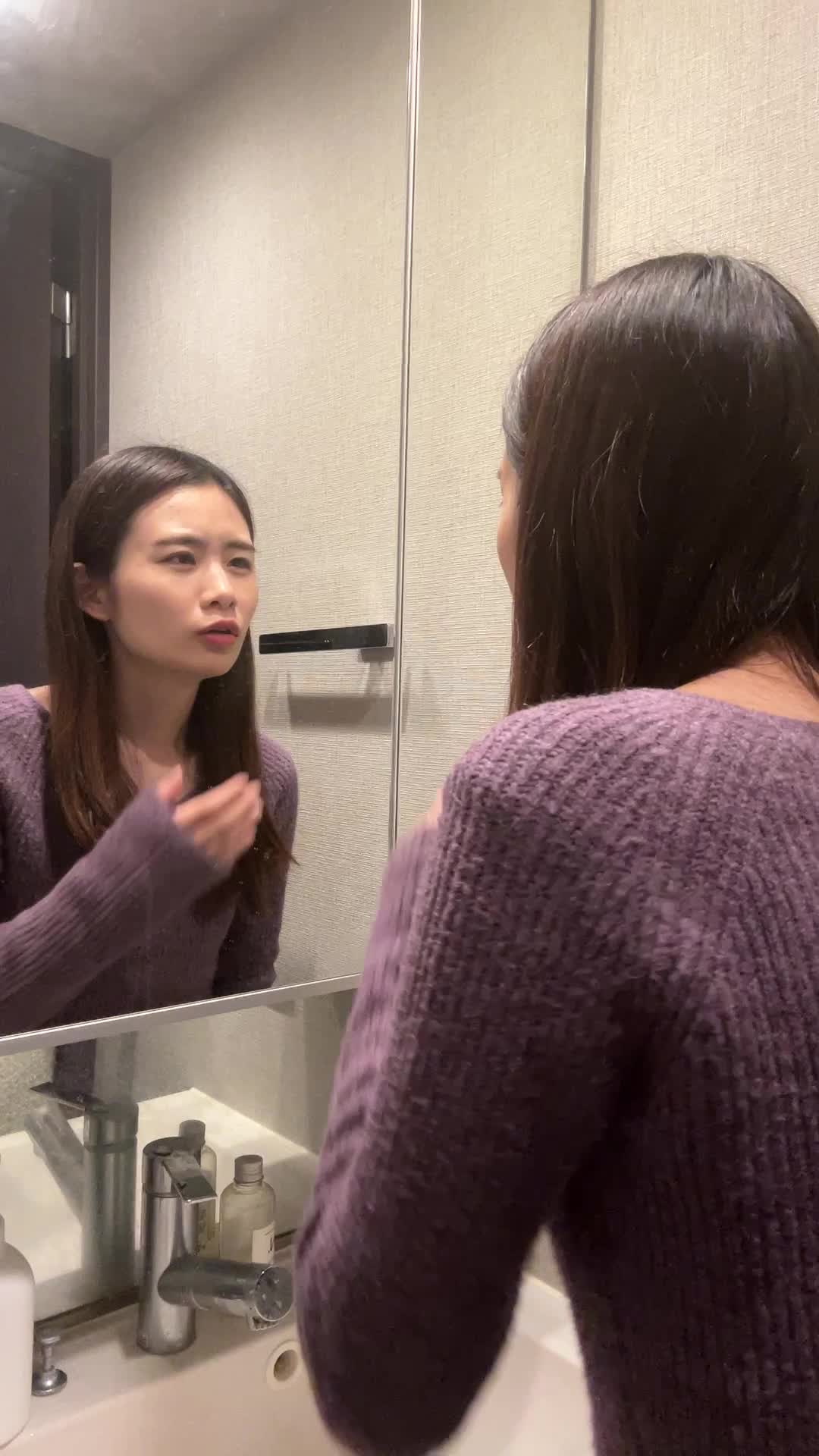 鏡の前で顔の左右を比べながら、「左右差が気になる」と指でなぞる動作