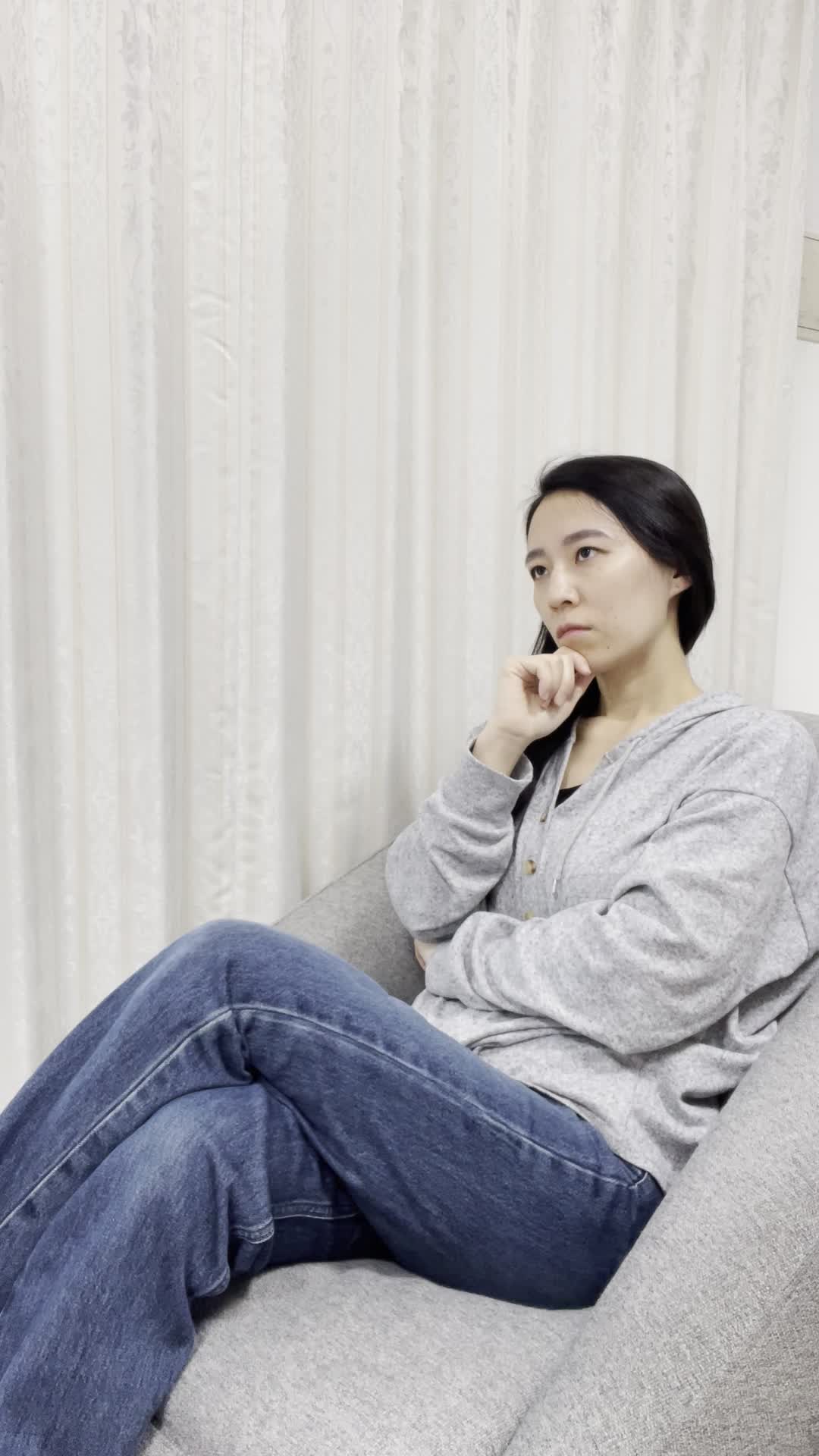 ソファで足を組み、「査定するならどこが一番いいんだろう？」と真剣に考える姿