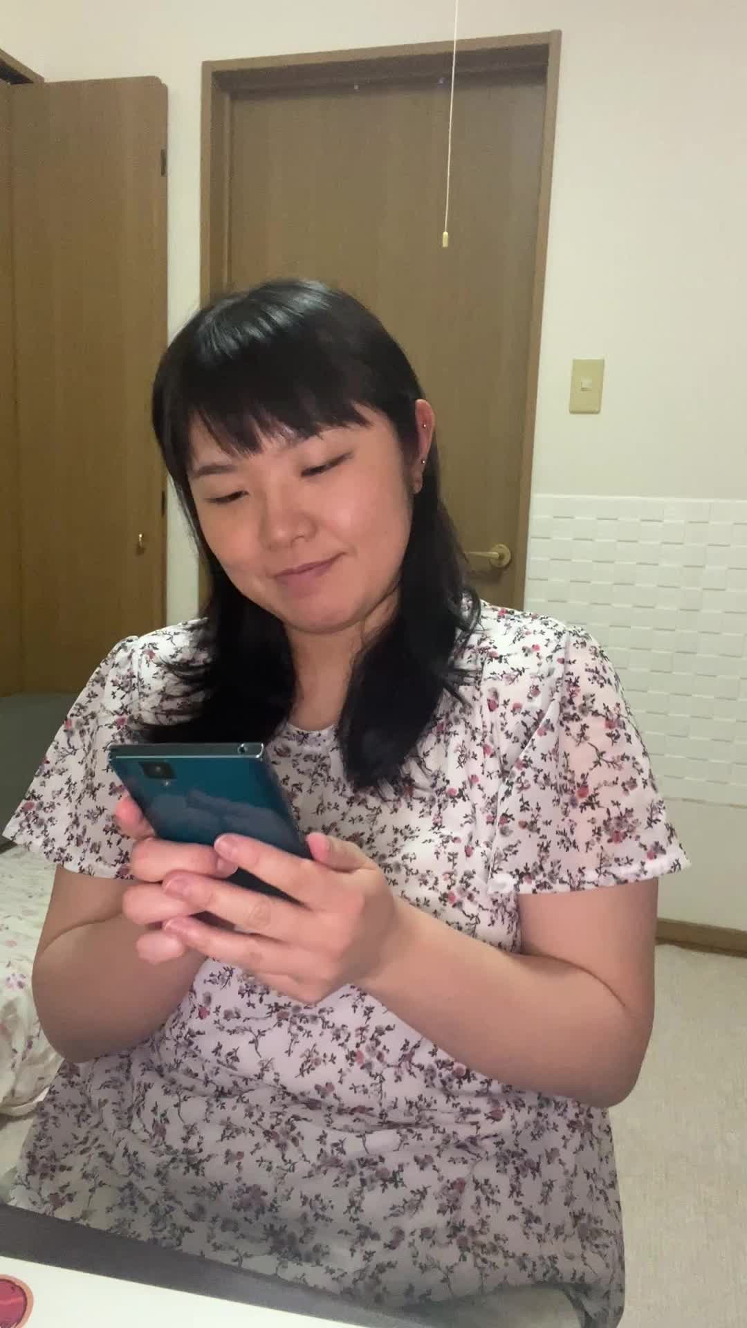 椅子に腰掛け、スマホのメッセージをじっと見つめて微笑むシーン