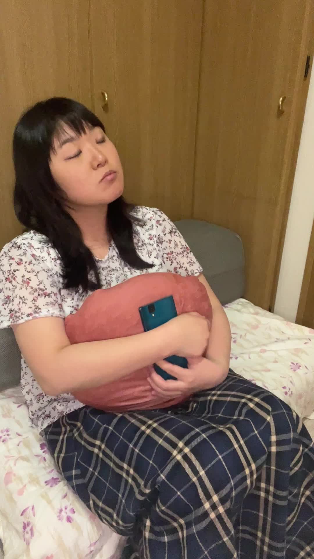 ソファでクッションを抱きしめながら、「今日も連絡ないのかな」と少し落ち込む表情