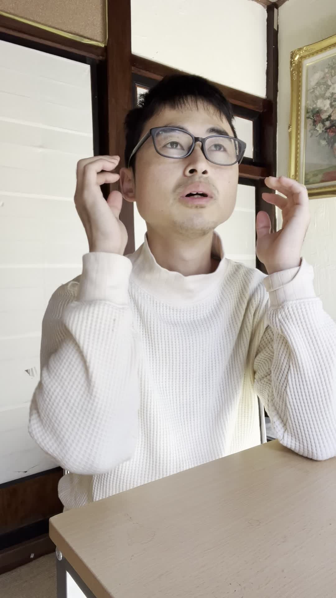 椅子に座り、手でこめかみを押さえながら「最近ずっと頭が重い」と困った表情