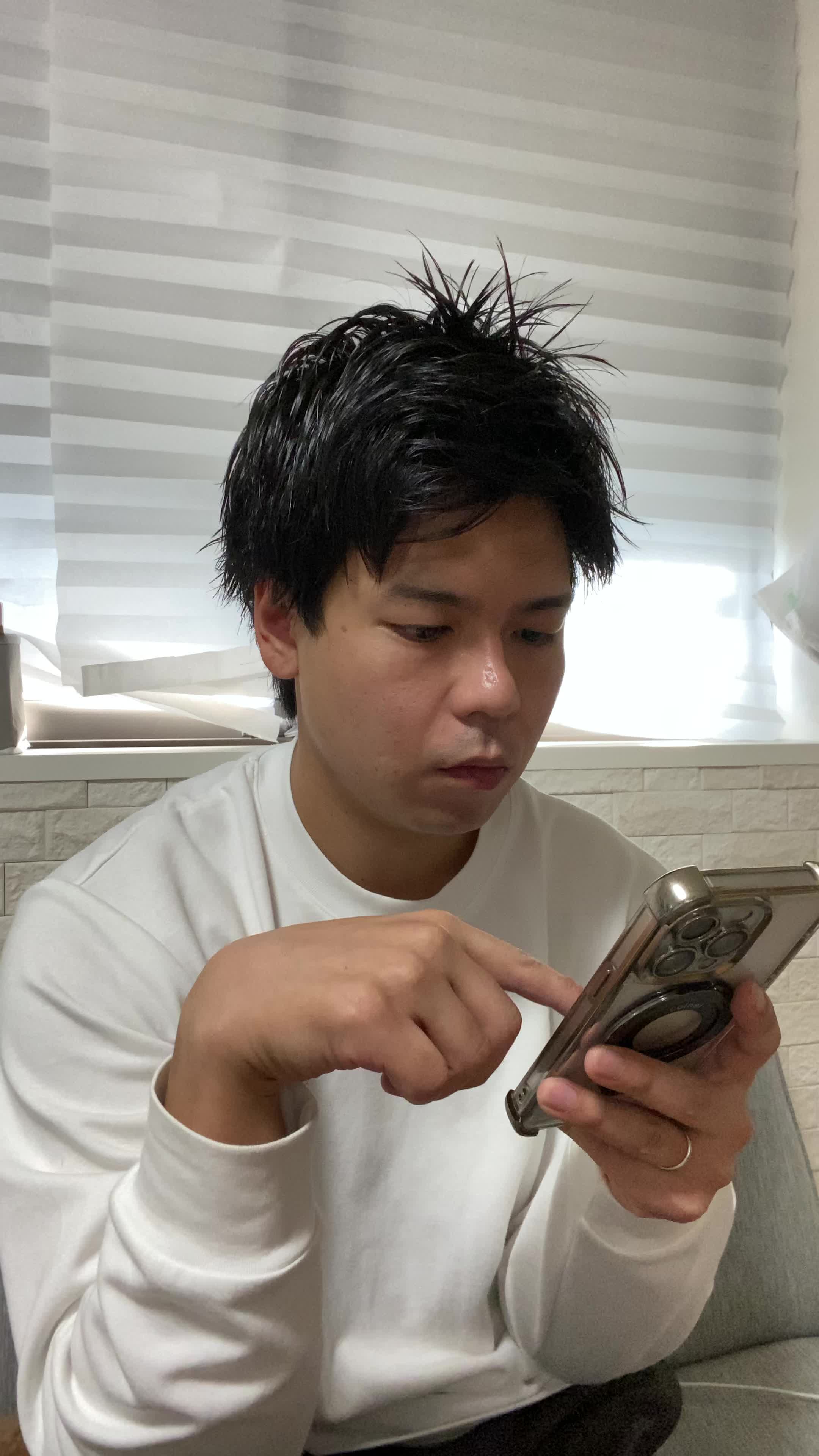 椅子に腰掛け、スマホの画面を見ながら「体臭ケアの口コミを読んで安心する」表情