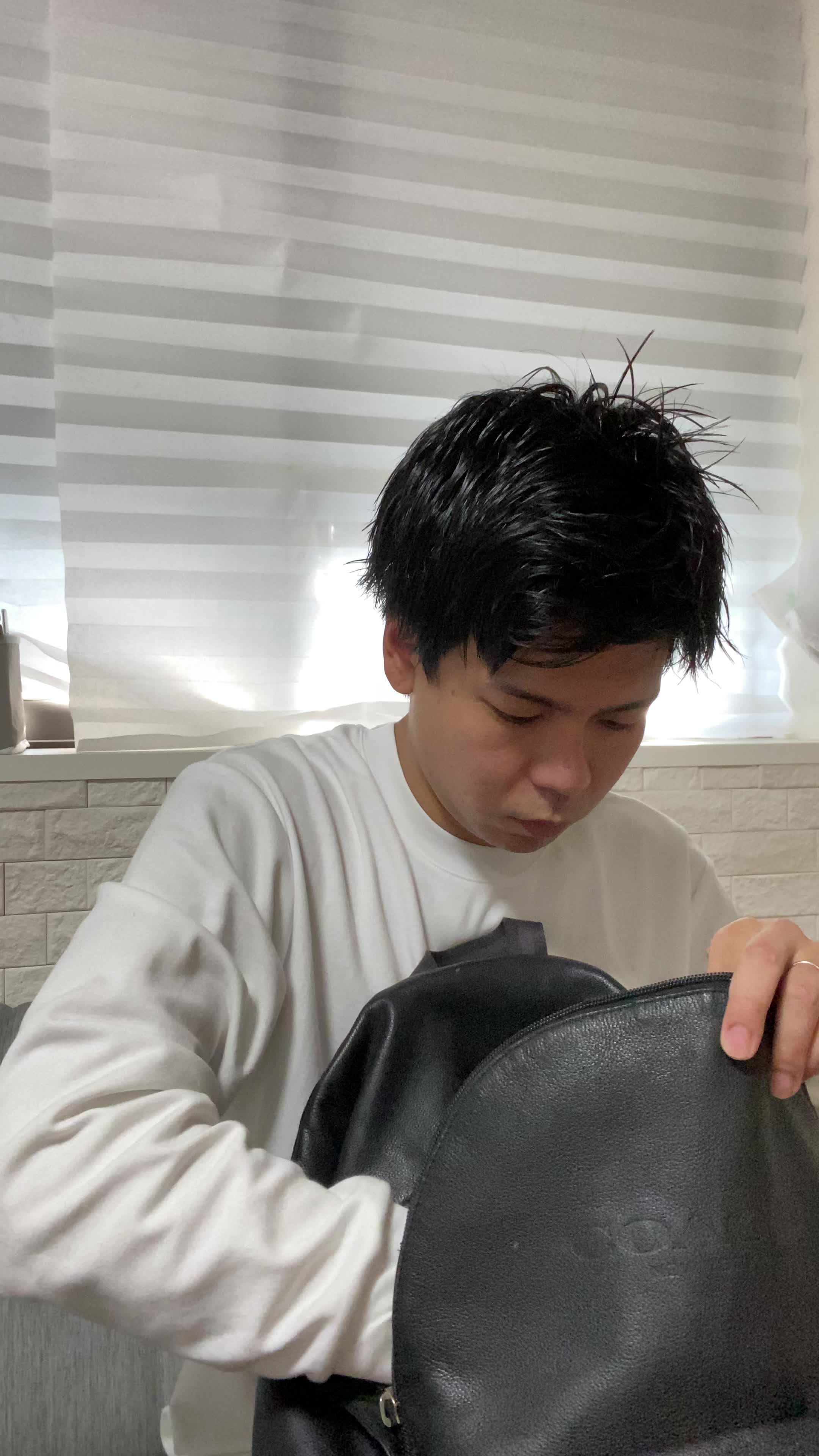 ソファでカバンの中を確認しながら、「体臭ケアスプレーを常備する」様子