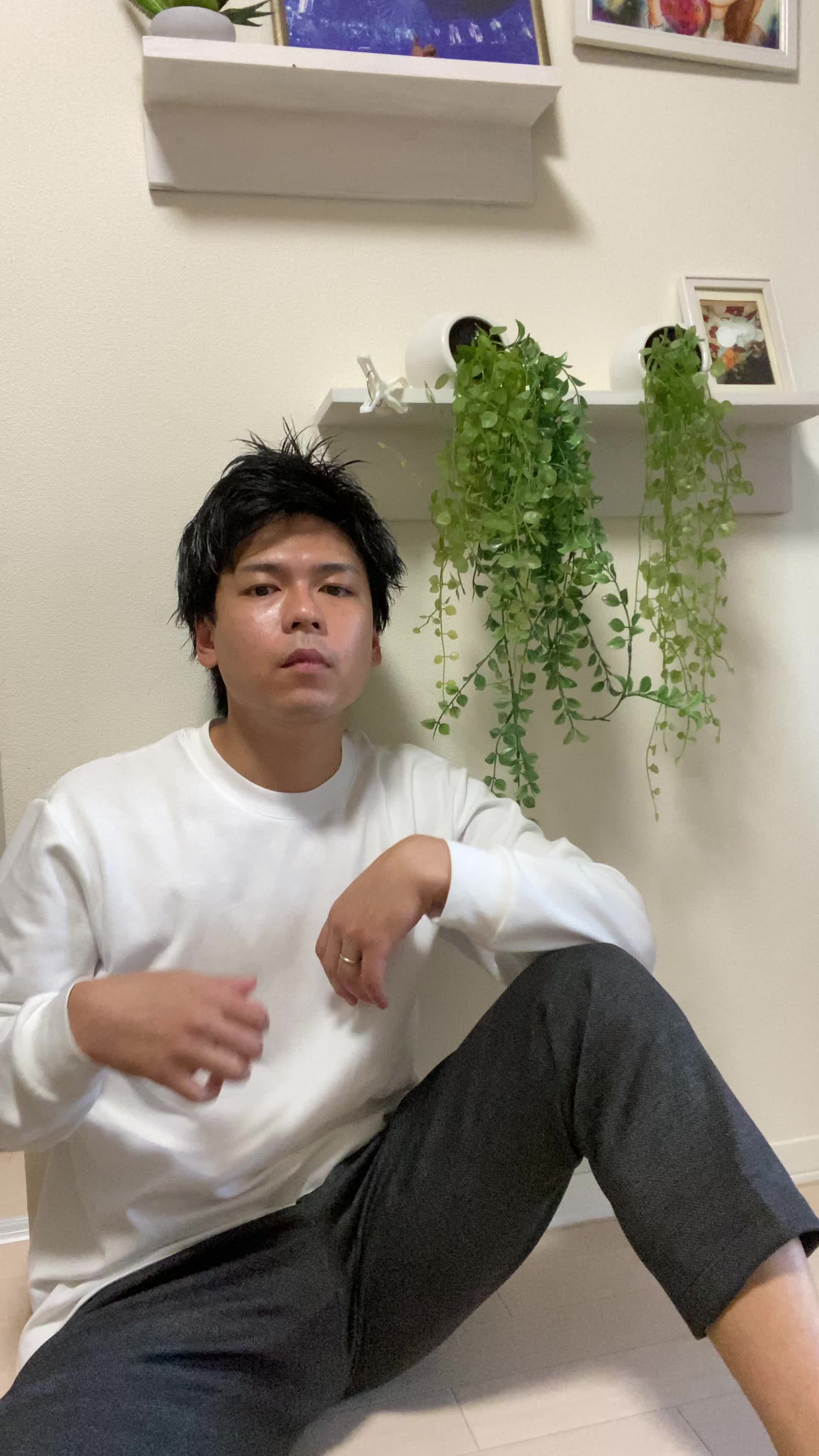 床に座り込み、自分のシャツを触りながら「このケアで変わるのかな」と考える仕草