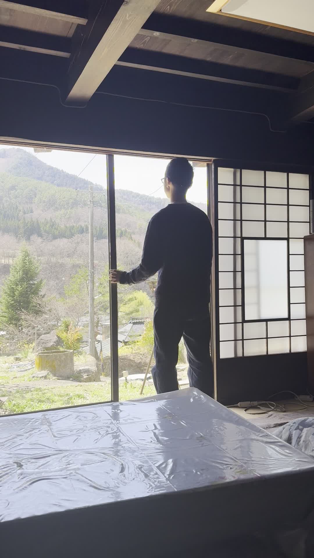 窓の方に歩いて行き、外を眺めながら軽く首を傾げる