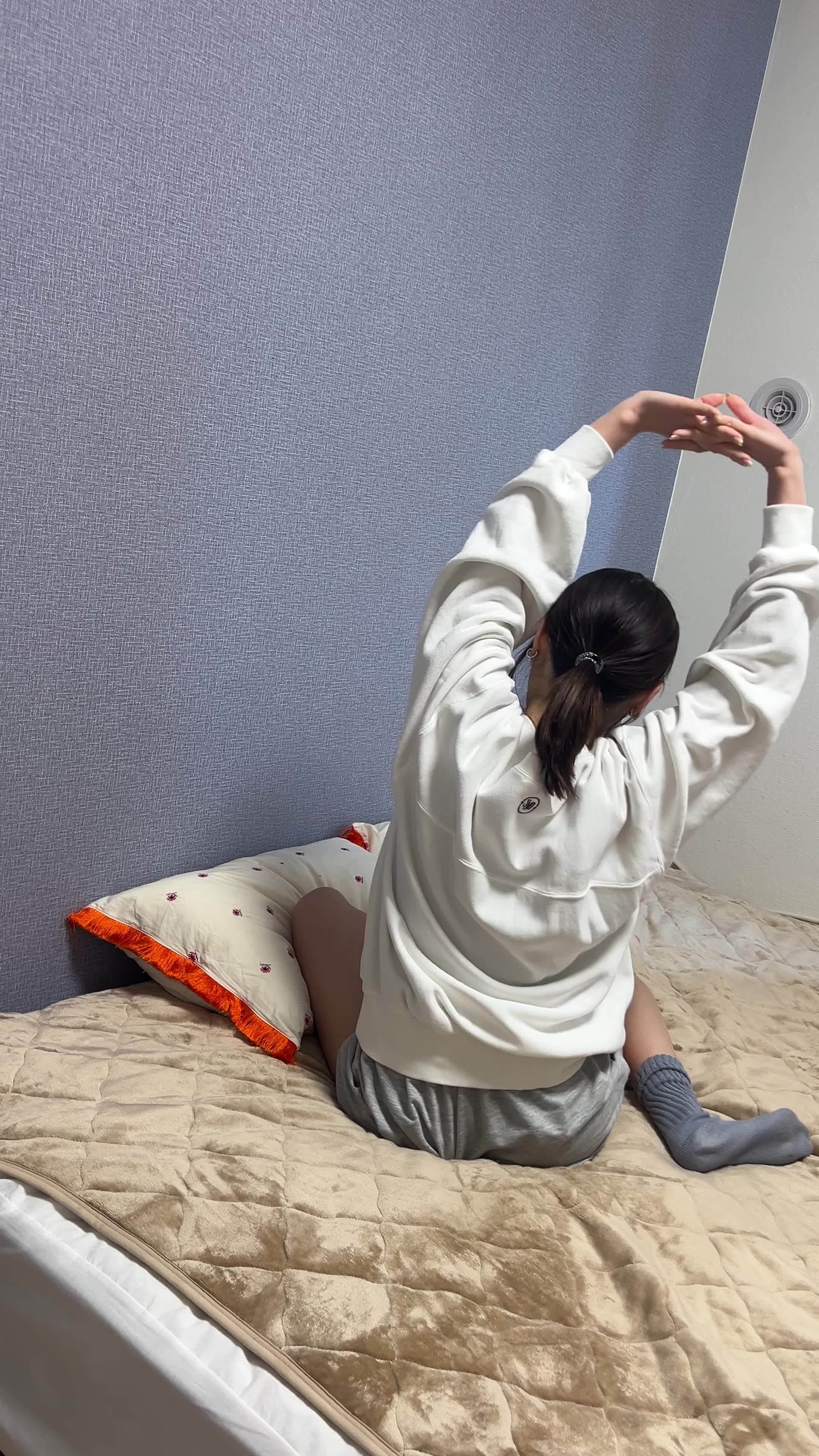 ベッドの上で伸びをする後ろ姿