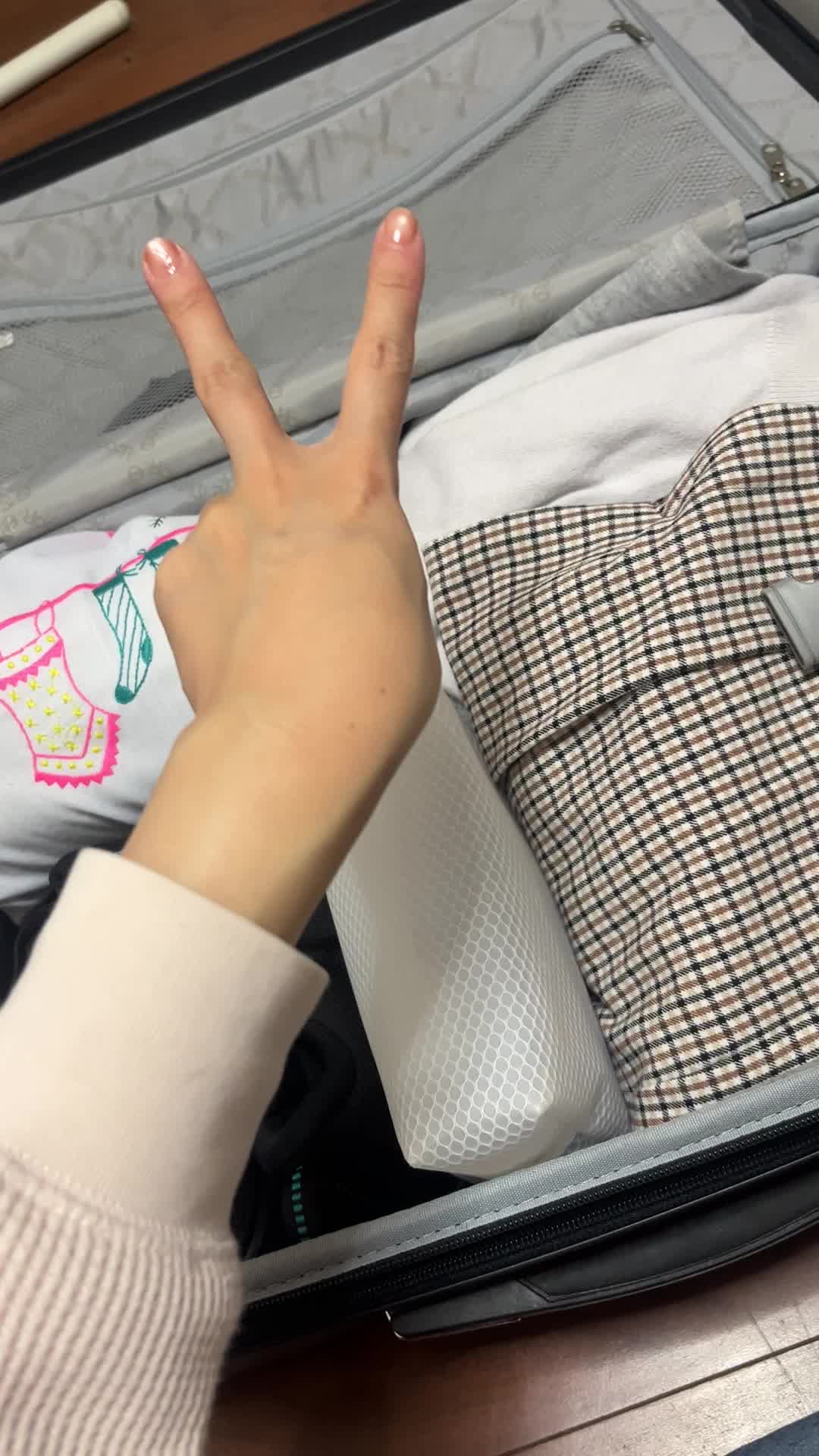 広げた荷物を背景にピースする手元