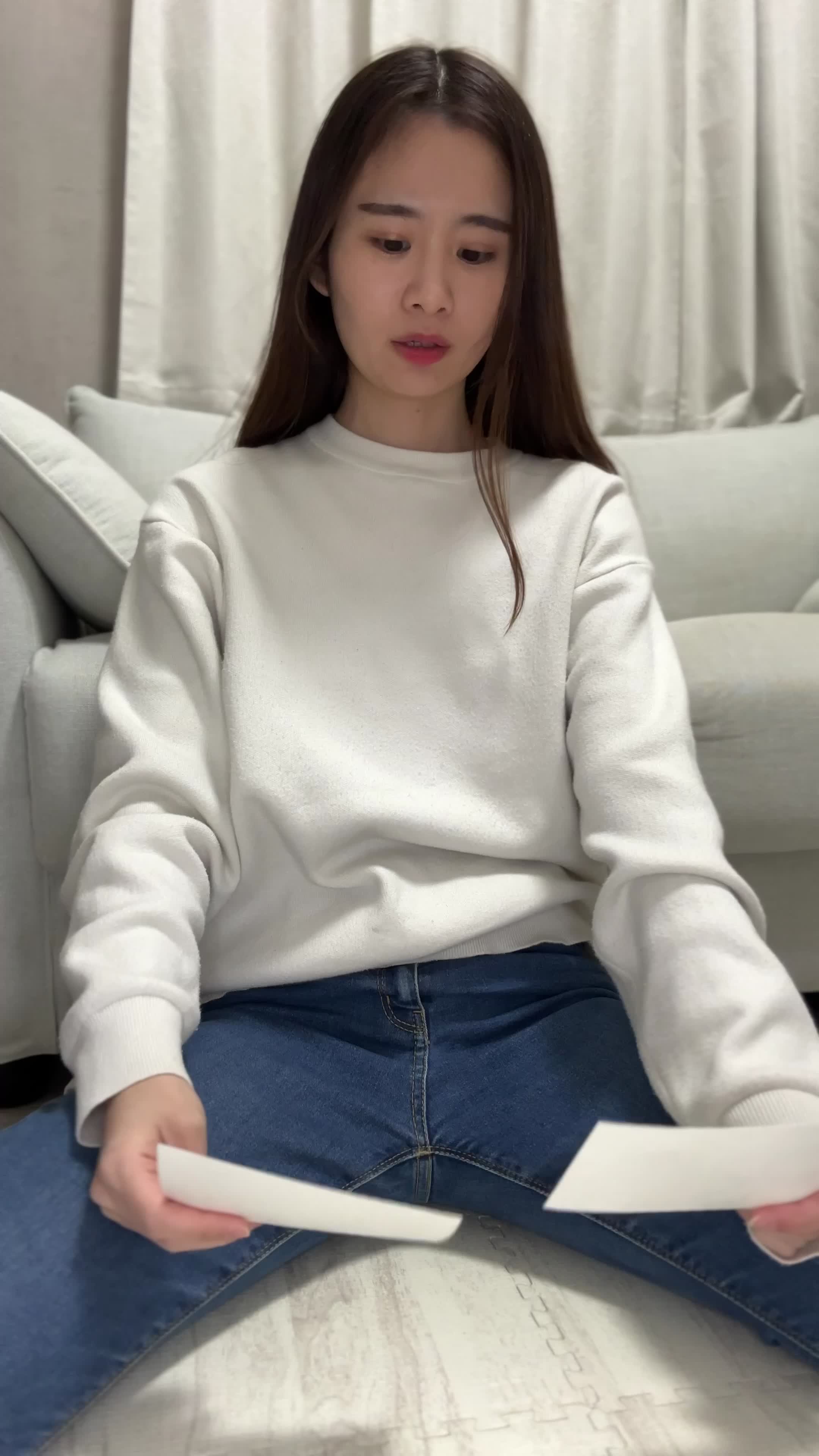 床に座り、車の写真を並べて「どれが高く売れるかな」と悩む様子