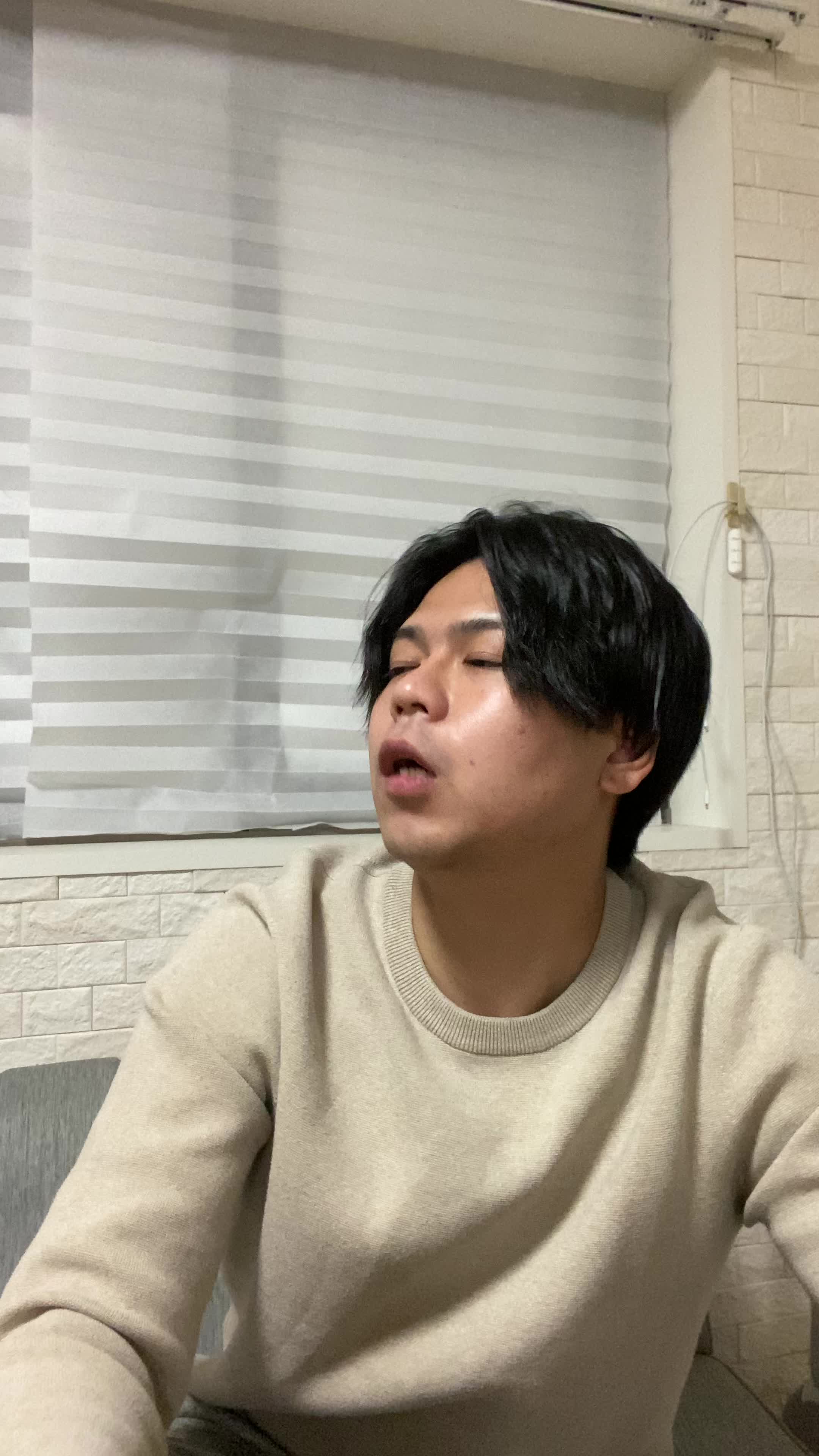 ソファで友達と話しながら、「自分の歯並びが気になる」と口元を隠す仕草