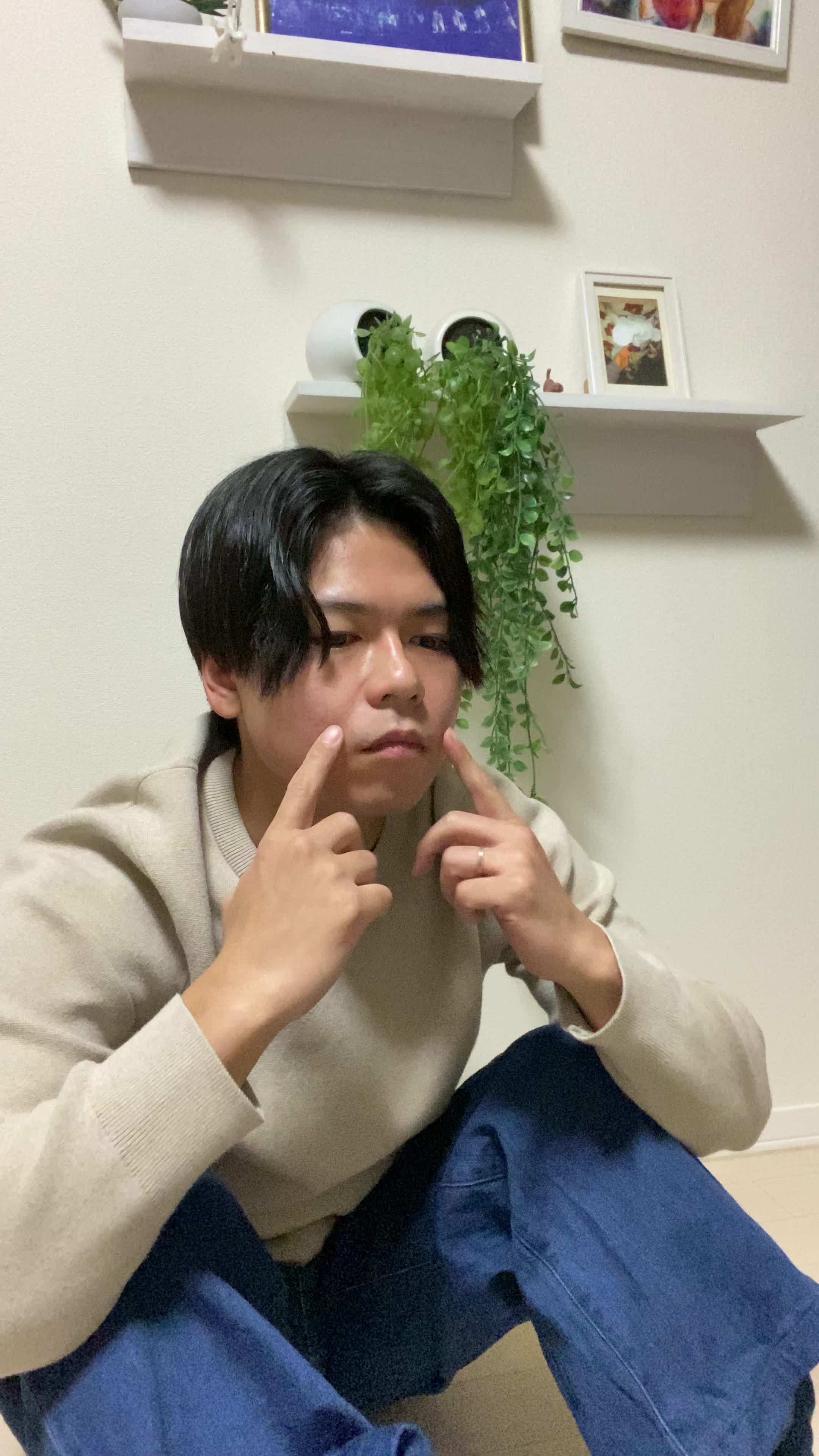 床で膝を抱え、「笑顔にもっと自信が持てるようになりたい」と考え込む様子