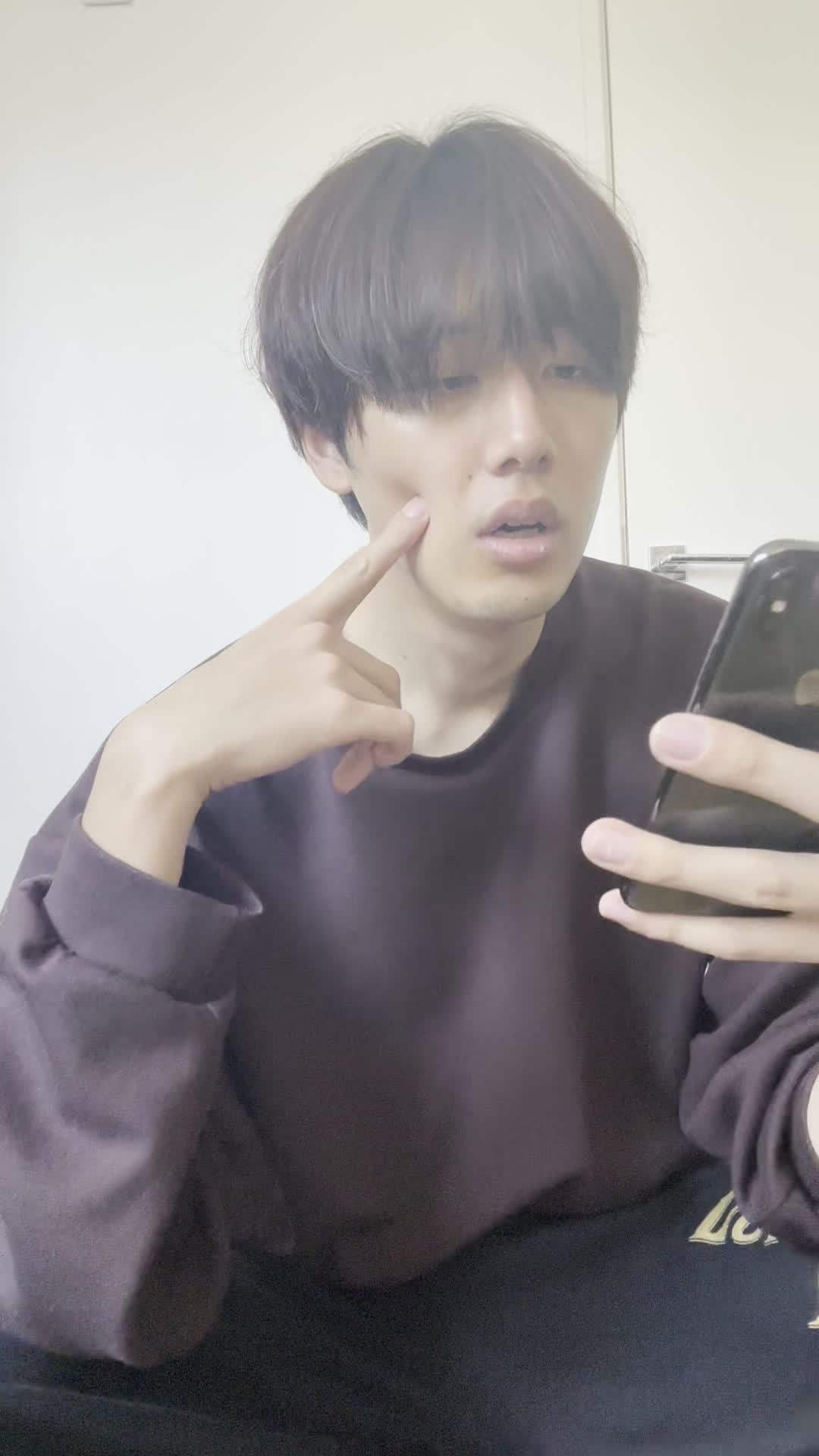椅子に座り、スマホでカートの中身を確認しながら「これ全部買おうかな？」と悩む表情
