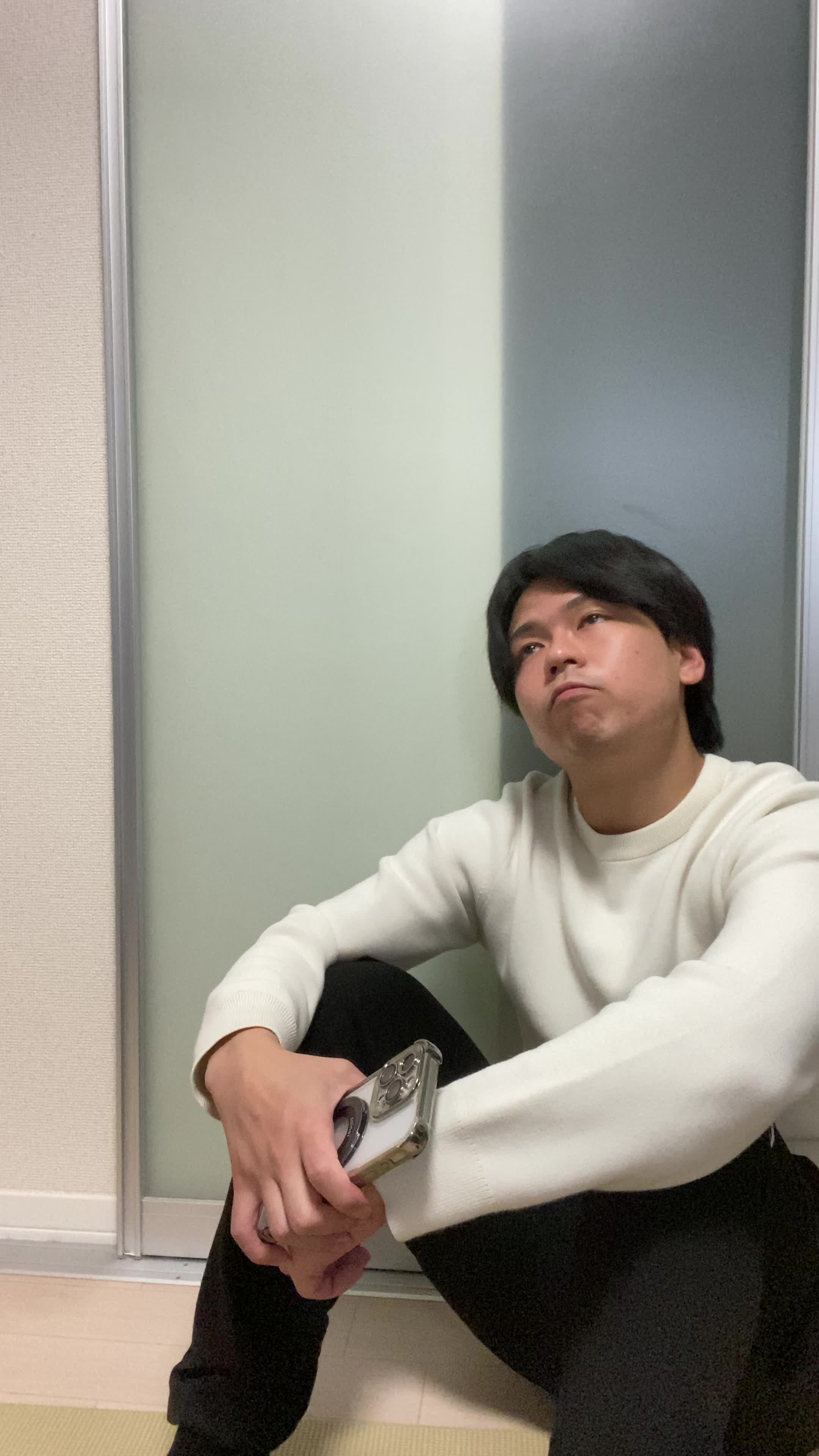 床で膝を立てて座り、「この白髪ケア商品を試してみようかな」と期待を込める動作