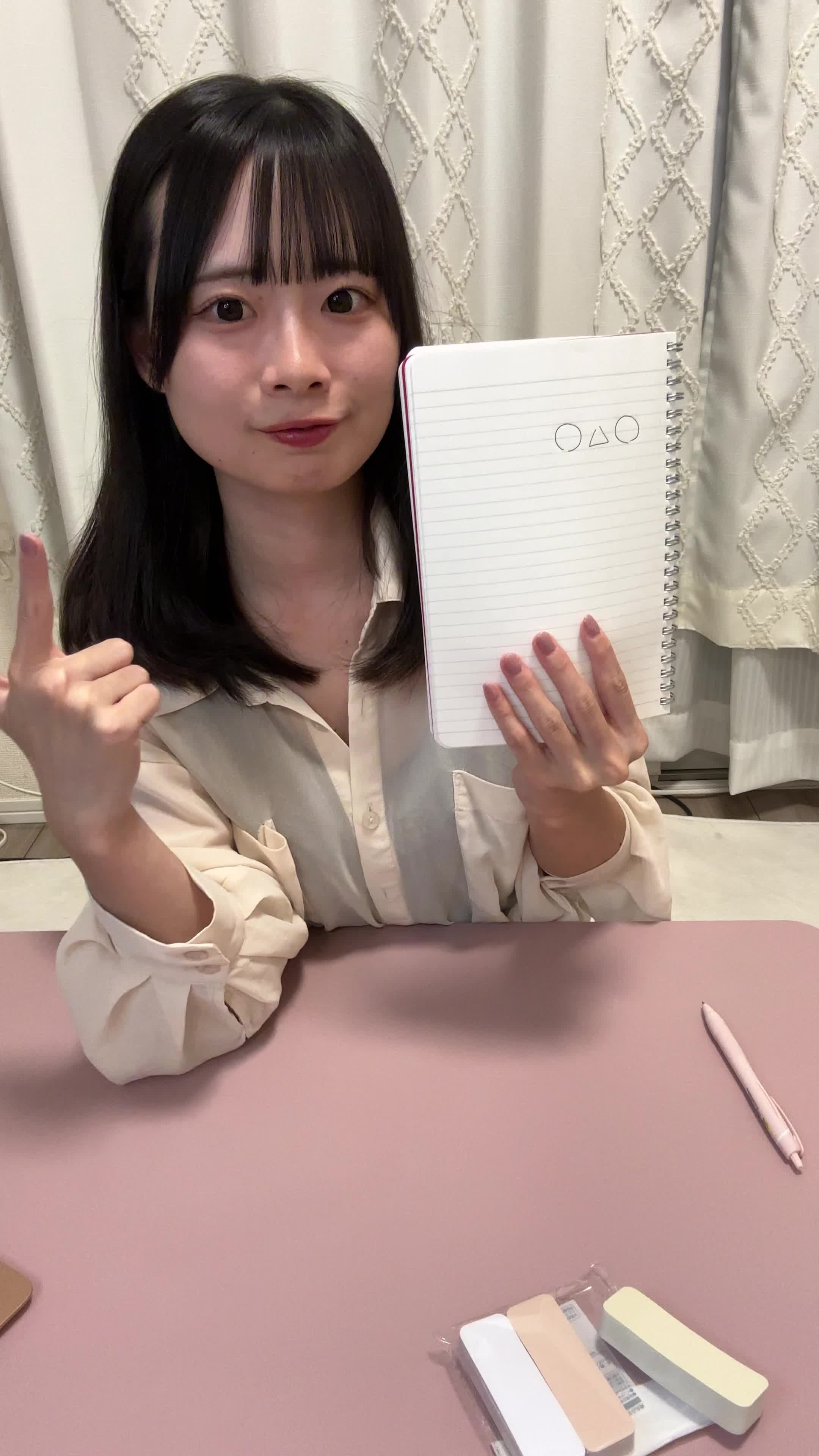 テーブルで紙に図を描いてカメラに向かって話しながら、「これが私の答えです」と説明する様子