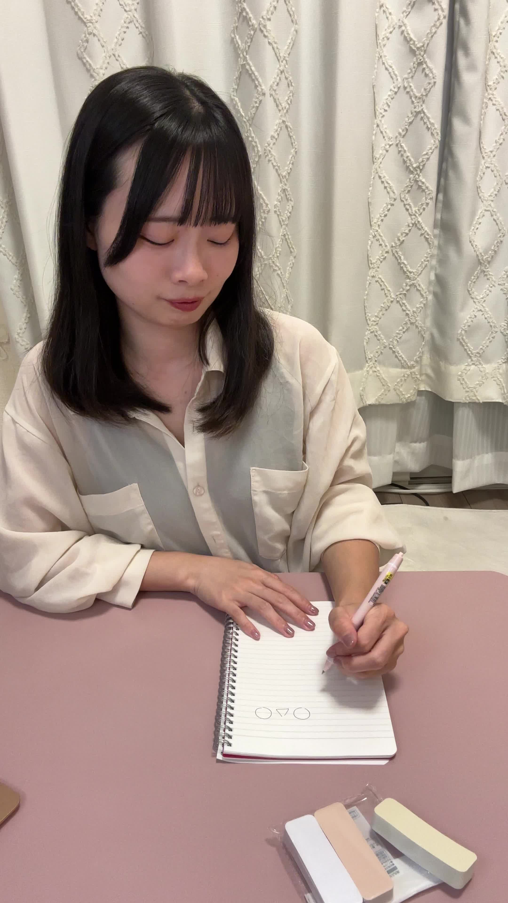 テーブルでペンを置き、「ついにできた！」と安堵して微笑む動作