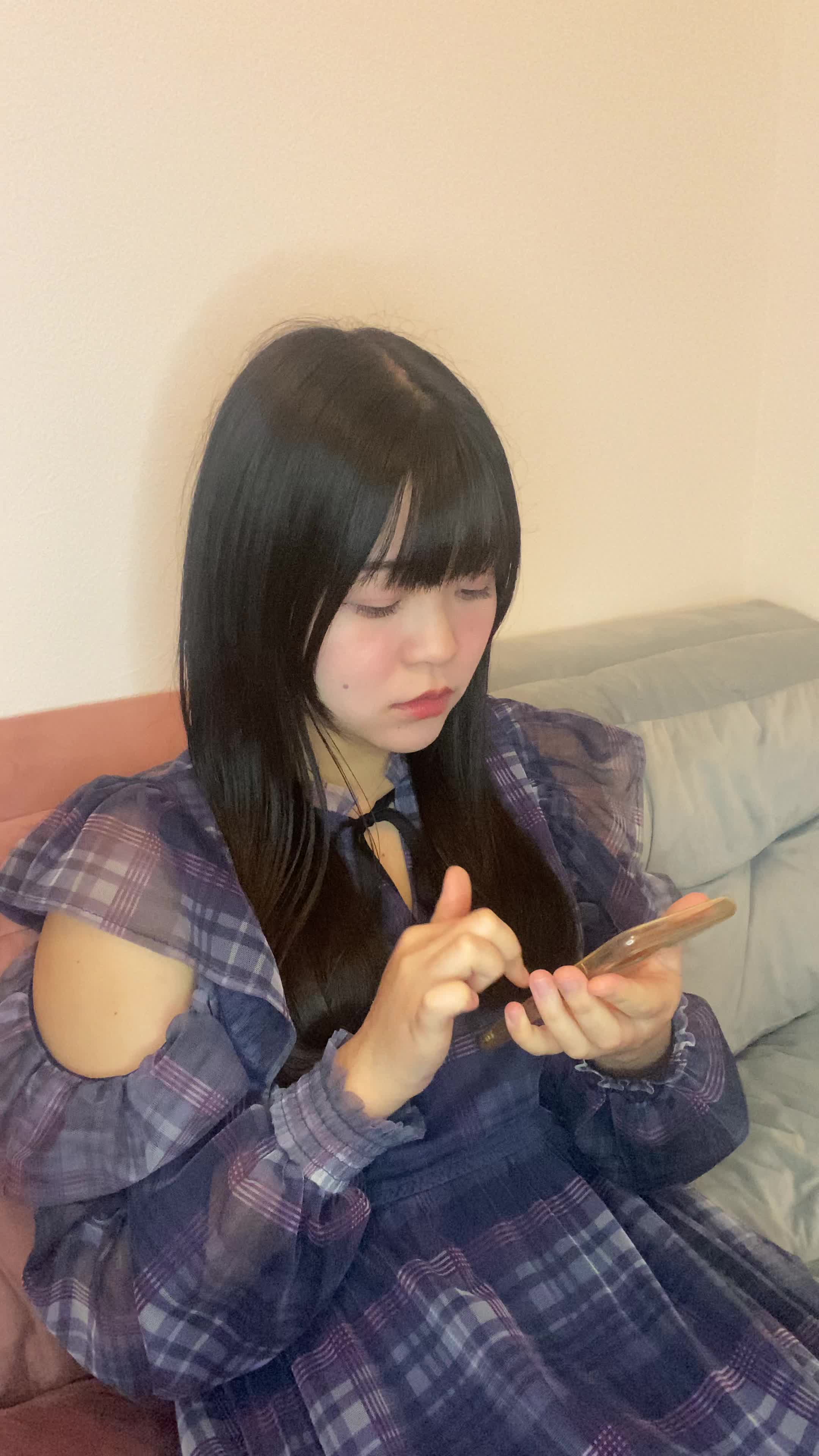 ソファに深く腰掛け、スマホを見ながら「どこに相談すればいいんだろう」と考え込む姿