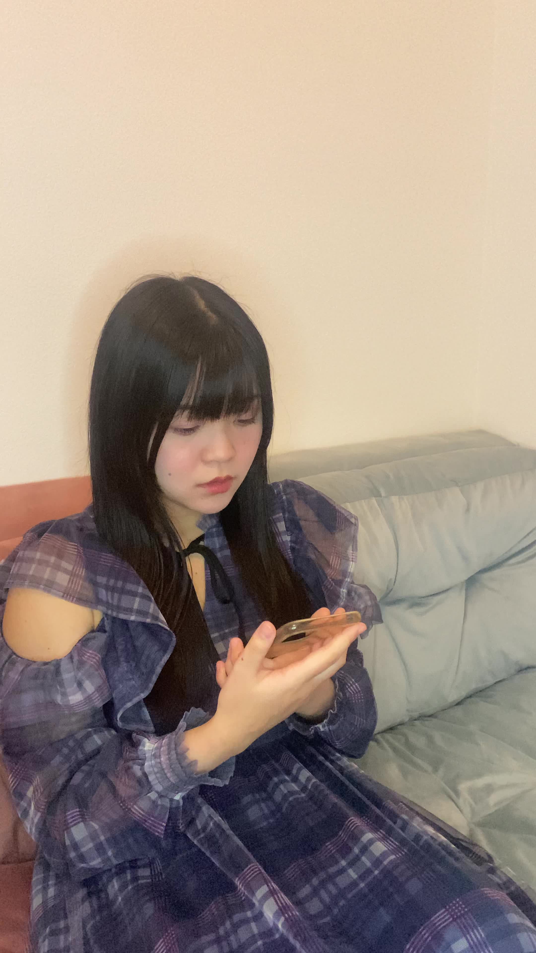 ソファでスマホに目を向け、「相談結果を待つ緊張感」を表現する動作