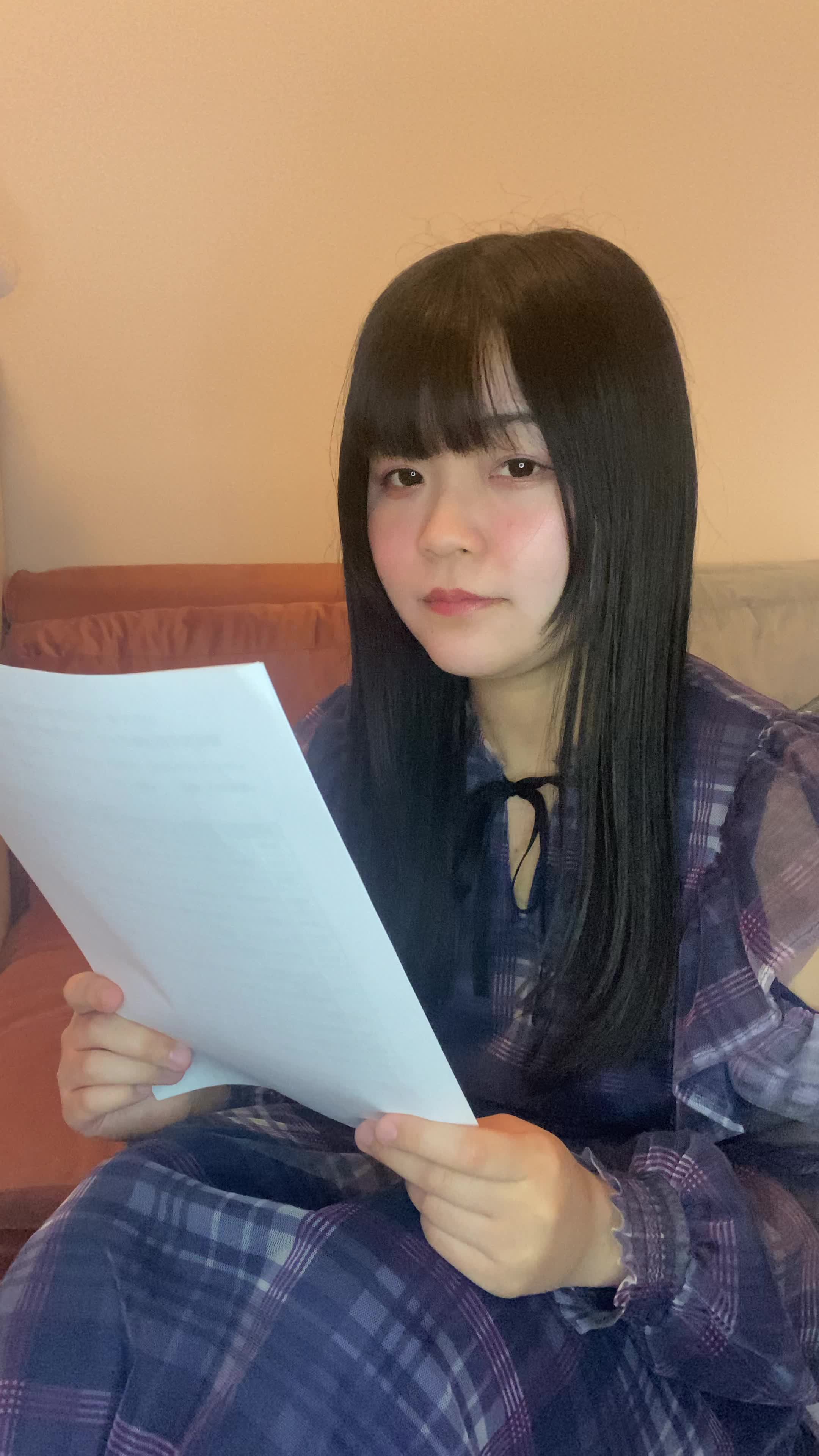 床に座り込み、資料を見つめて「これで解決するのかな」と希望を見出す表情