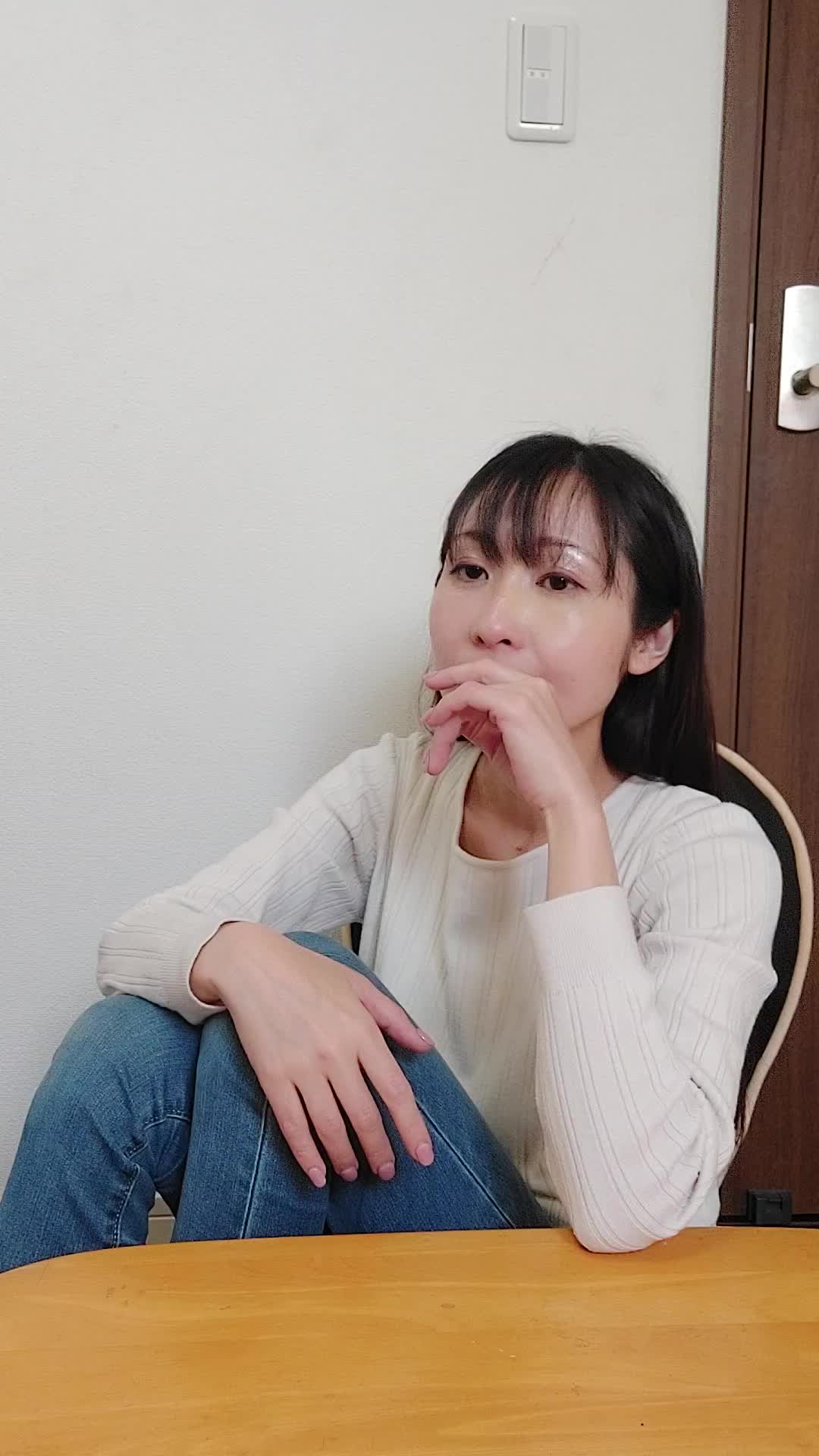 椅子に座り友達と話しながら、「自分の歯並びが気になる」と口元を隠す仕草