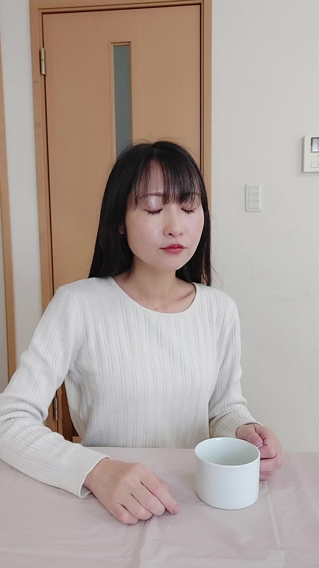 テーブルでカップを手に取り、「矯正中でも食べやすいメニュー」を考える表情