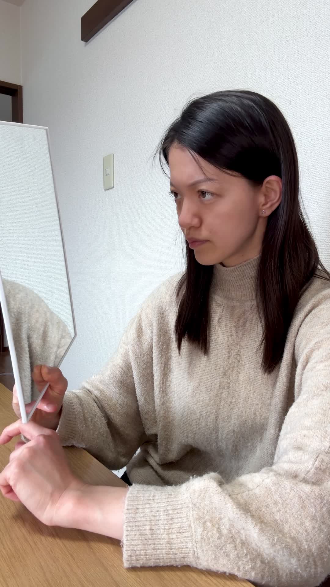 テーブルで鏡を手に取り、「白髪の変化をじっくり確認する」動作