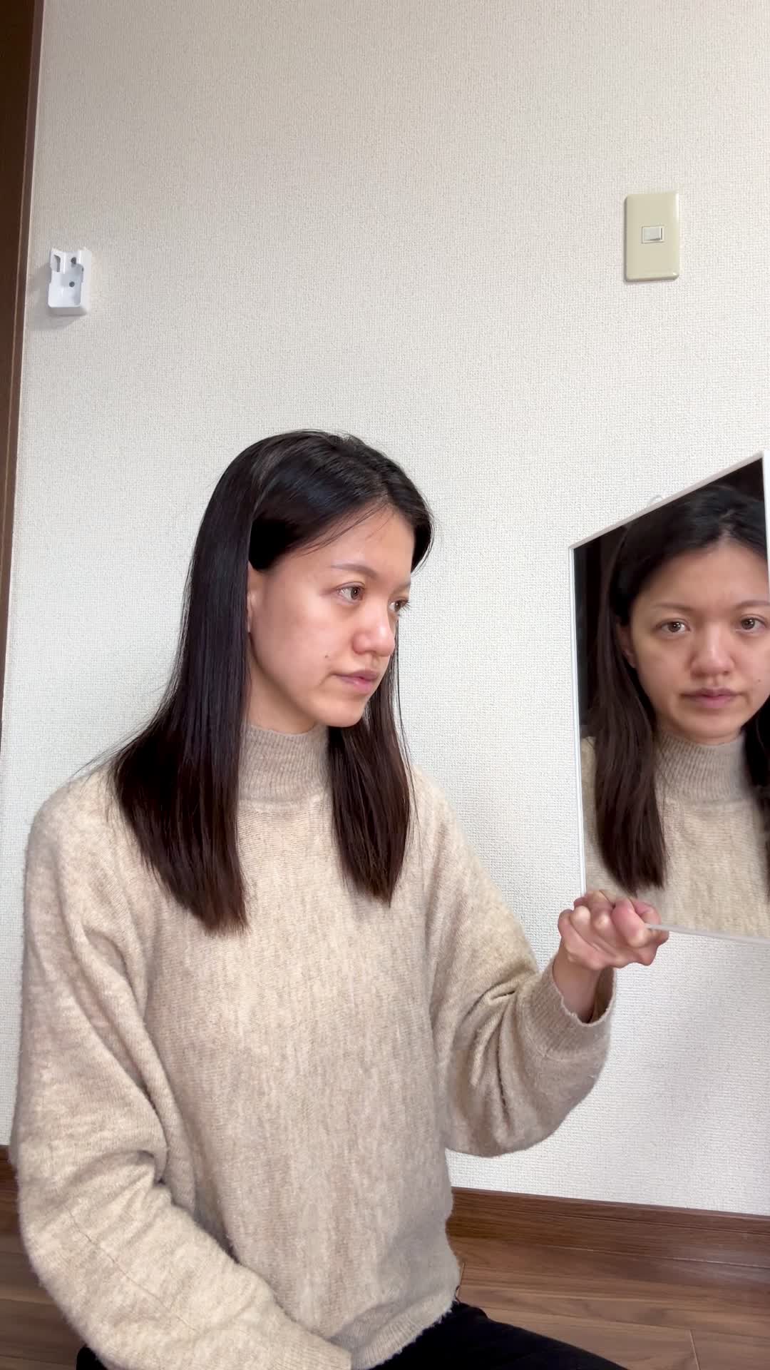 床に座り込み、鏡を近づけて白髪をじっくり確認し、「これがなくなれば…」と考える仕草