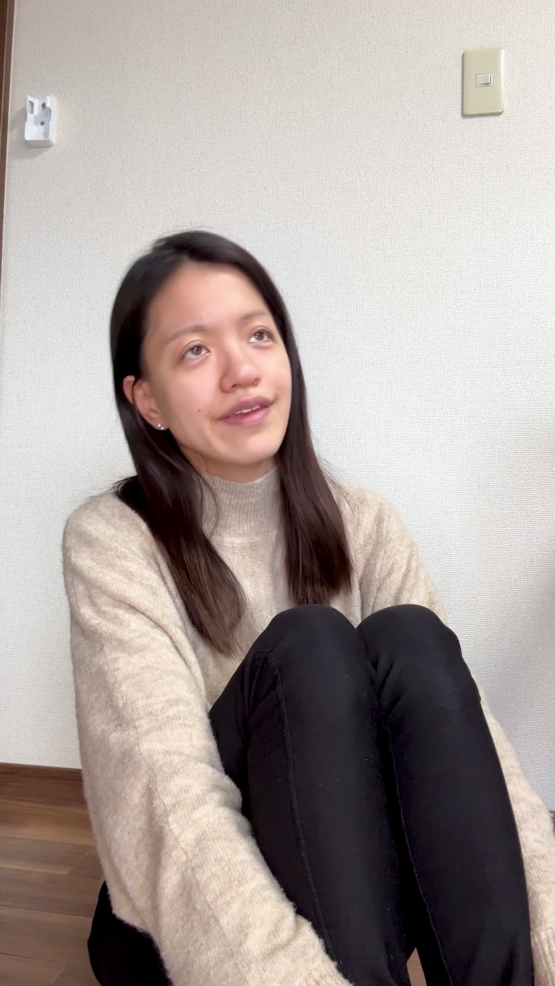 床で膝を立てて座り、「この白髪ケア商品を試してみようかな」と期待を込める動作