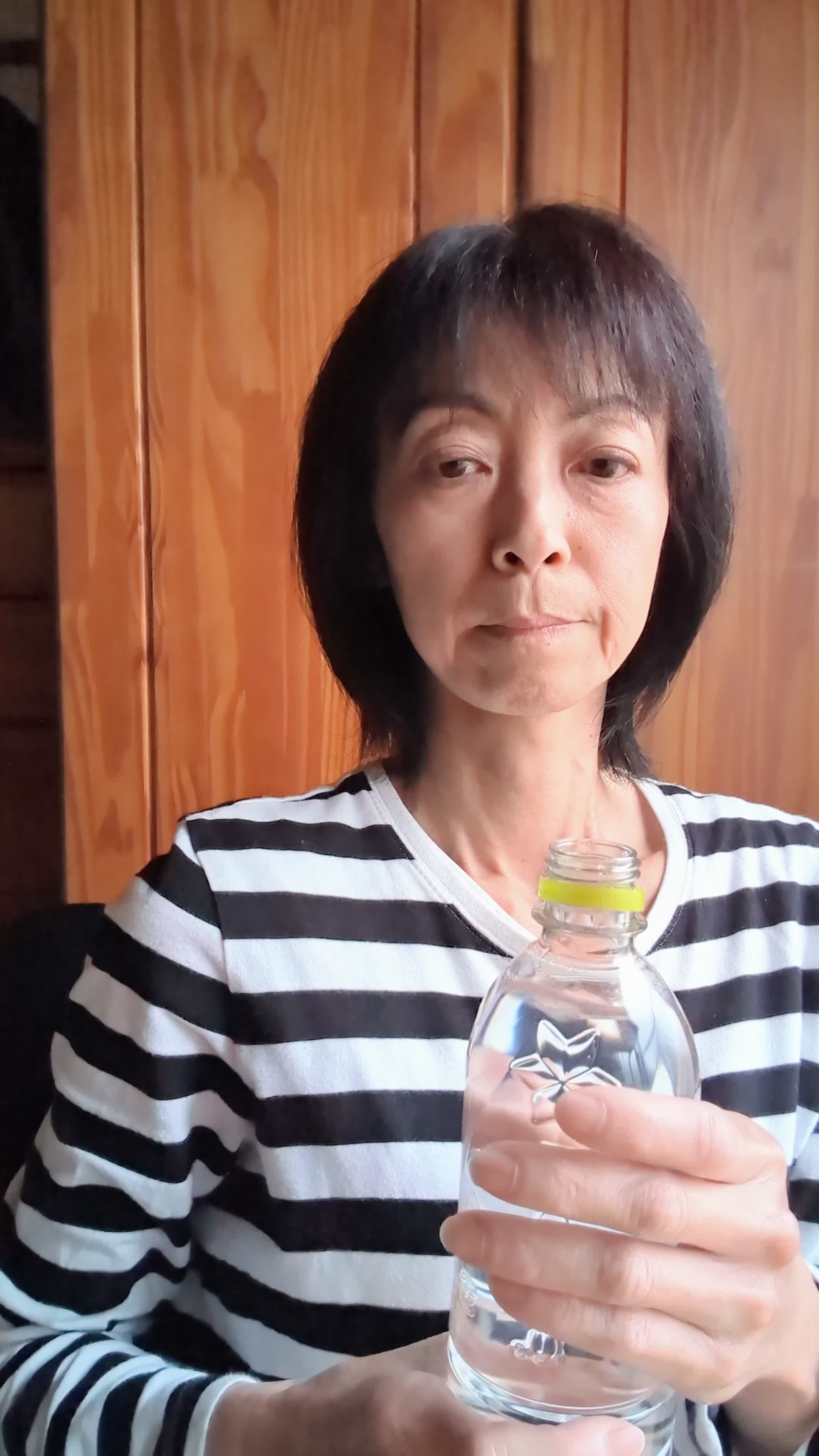 椅子に座り、ペットボトルの水を飲みながら「もっと手軽に冷たい水が飲めたらいいのに」と考える表情