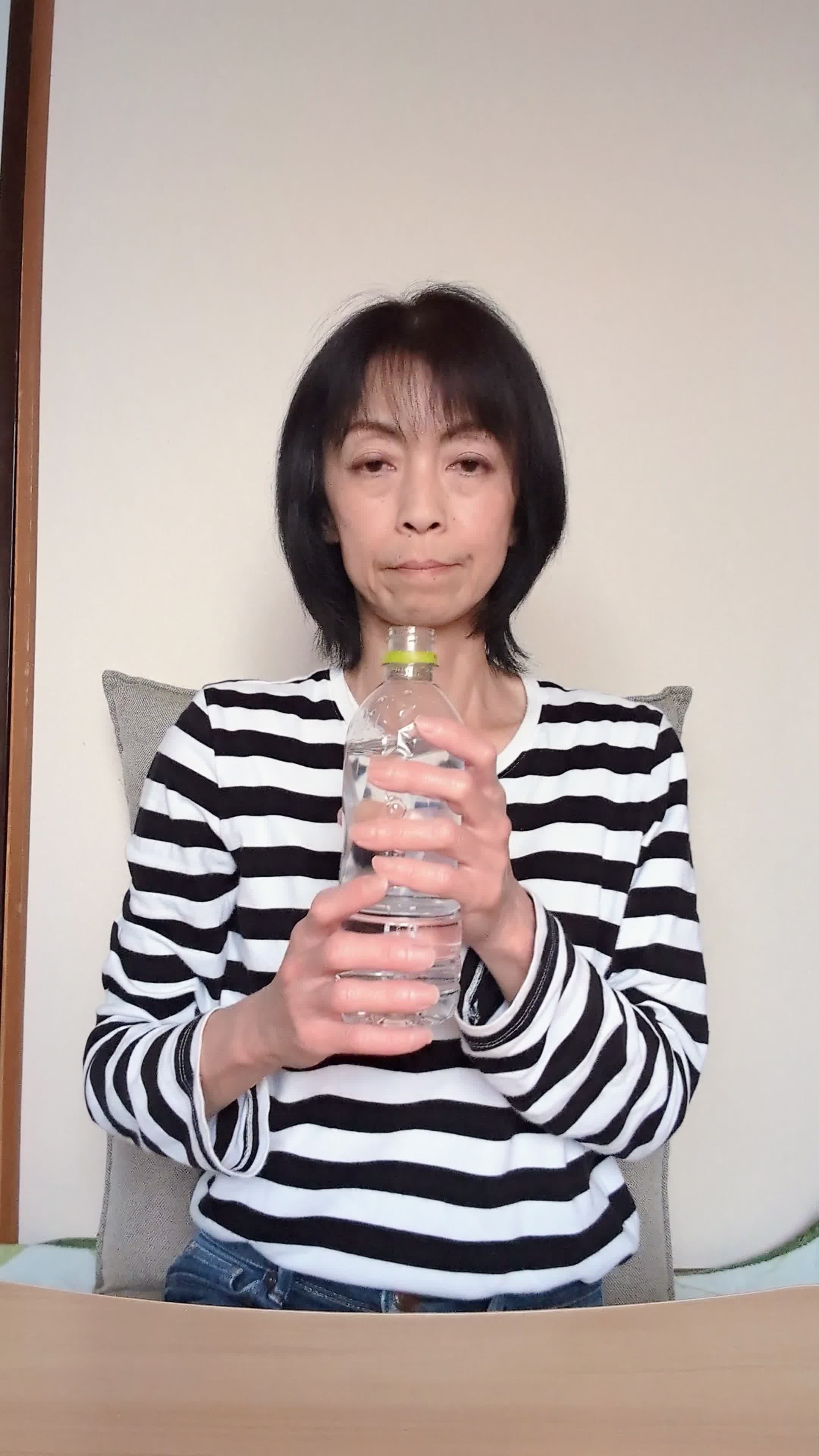 テーブルで水を飲み、「これがいつでも手軽に取れたら…」と空想する表情