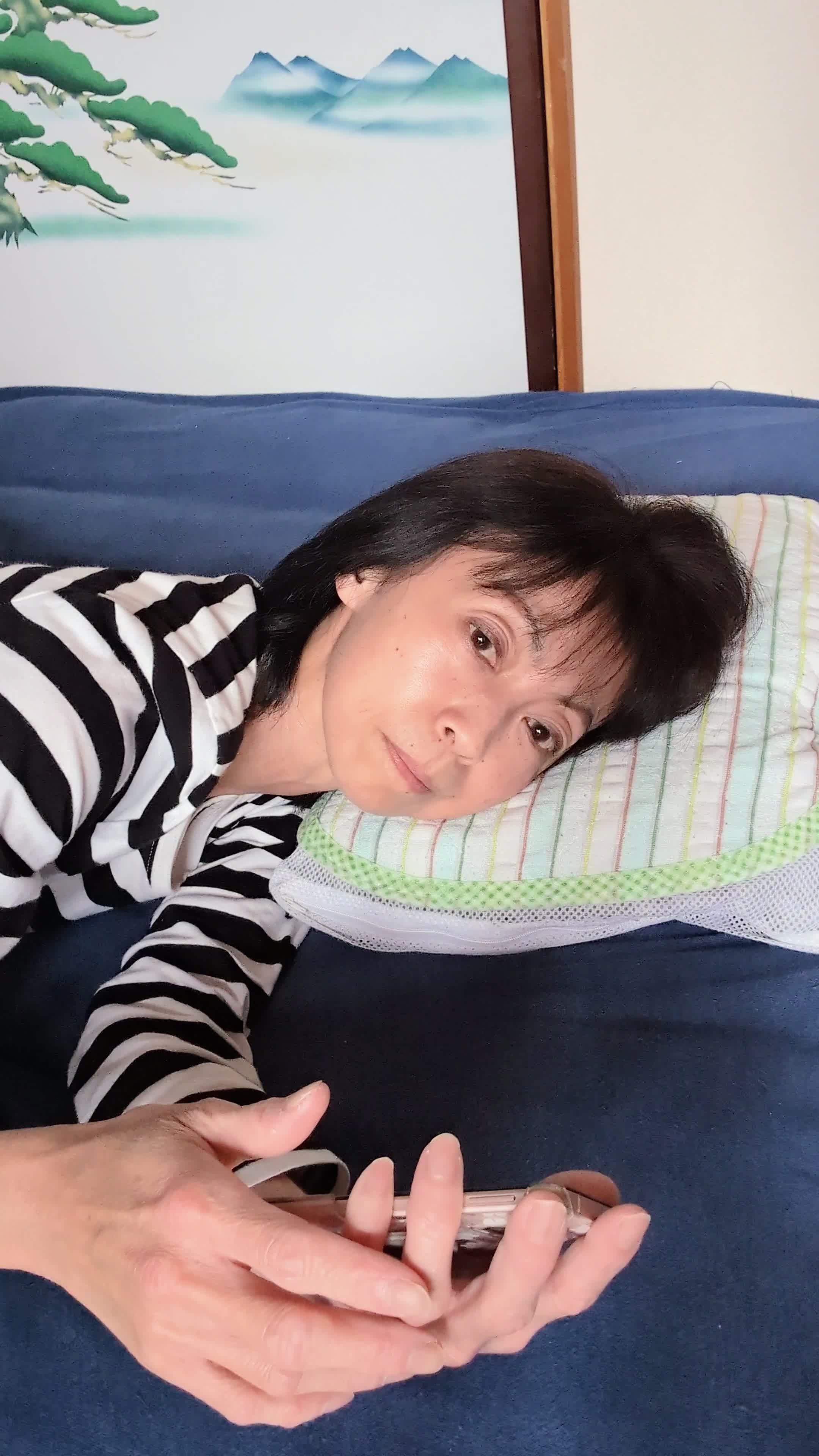 ベッドで横になり、「夜中に喉が渇いたとき、すぐに水があれば…」とスマホを見つめる姿