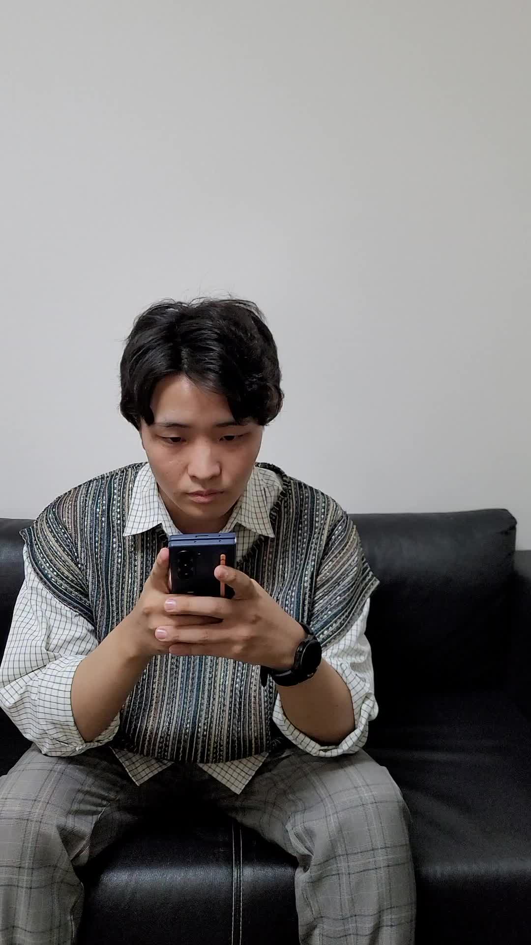 ソファでスマホを眺めながら、「応募結果を待ちながら少し緊張する」表情