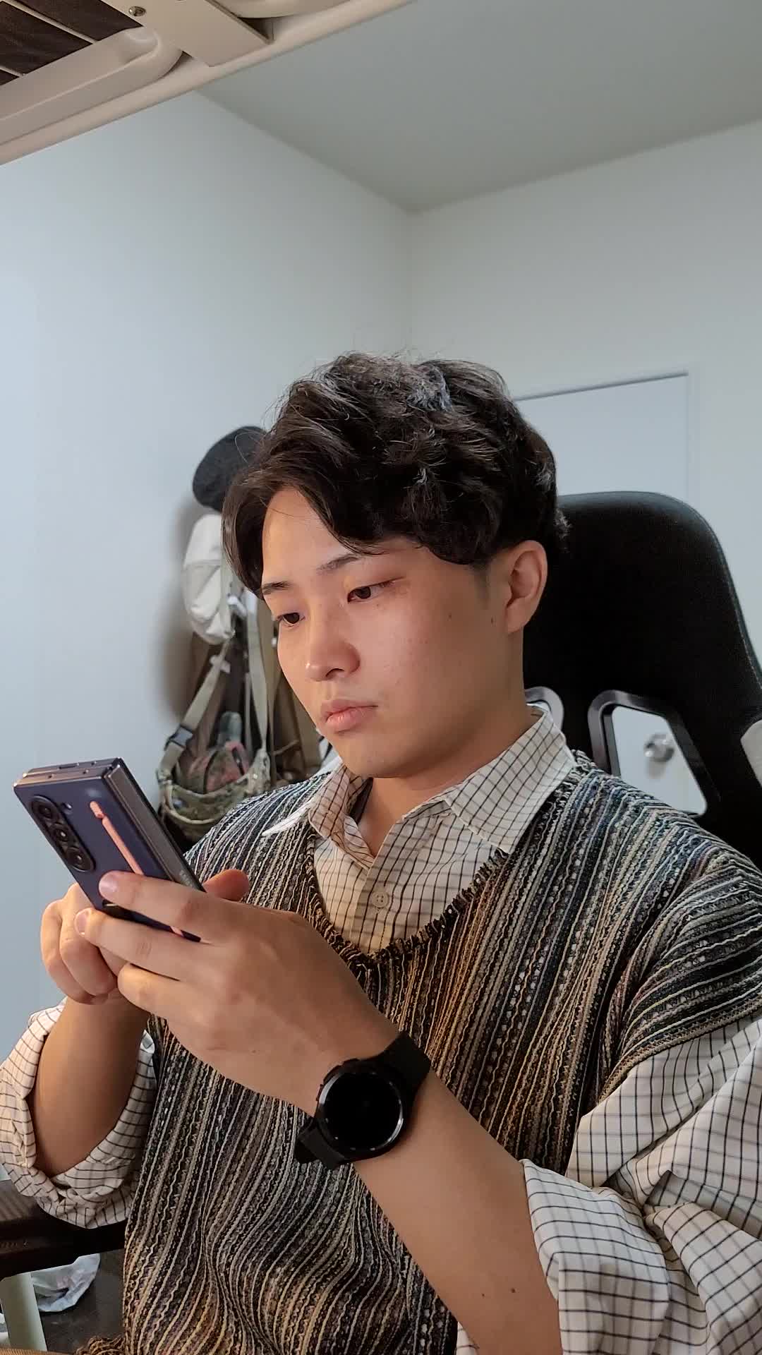 椅子に座り、スマホで求人情報を眺めながら「どれが自分に合うだろう」と悩む表情