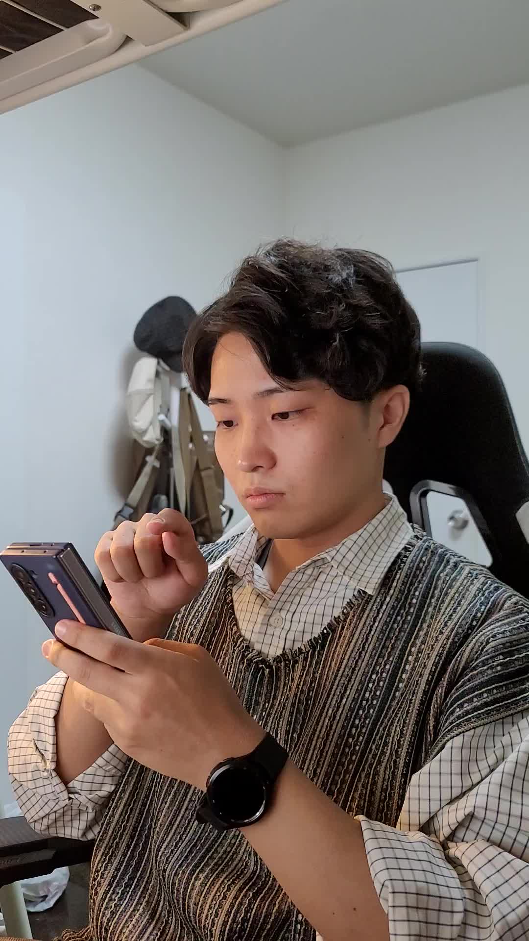 椅子に腰掛け、「スマホの求人アプリを操作して理想の条件を探す」動作