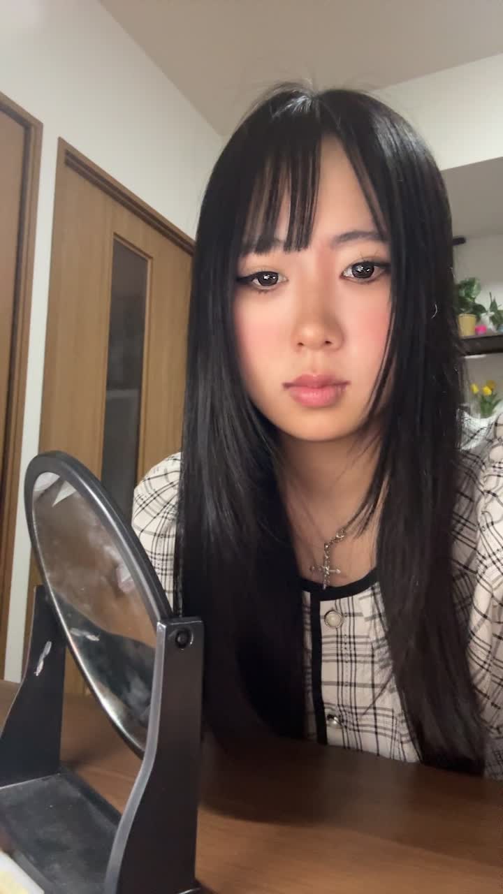 鏡の前で髪の分け目をじっと観察しながら少し真剣な表情を見せる