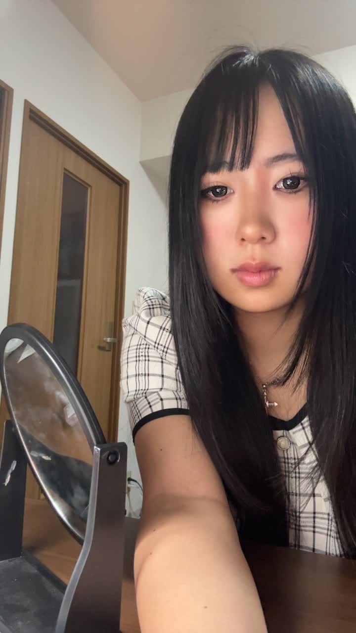鏡を見つめながら、髪を軽く引っ張り状態を確認する仕草をする