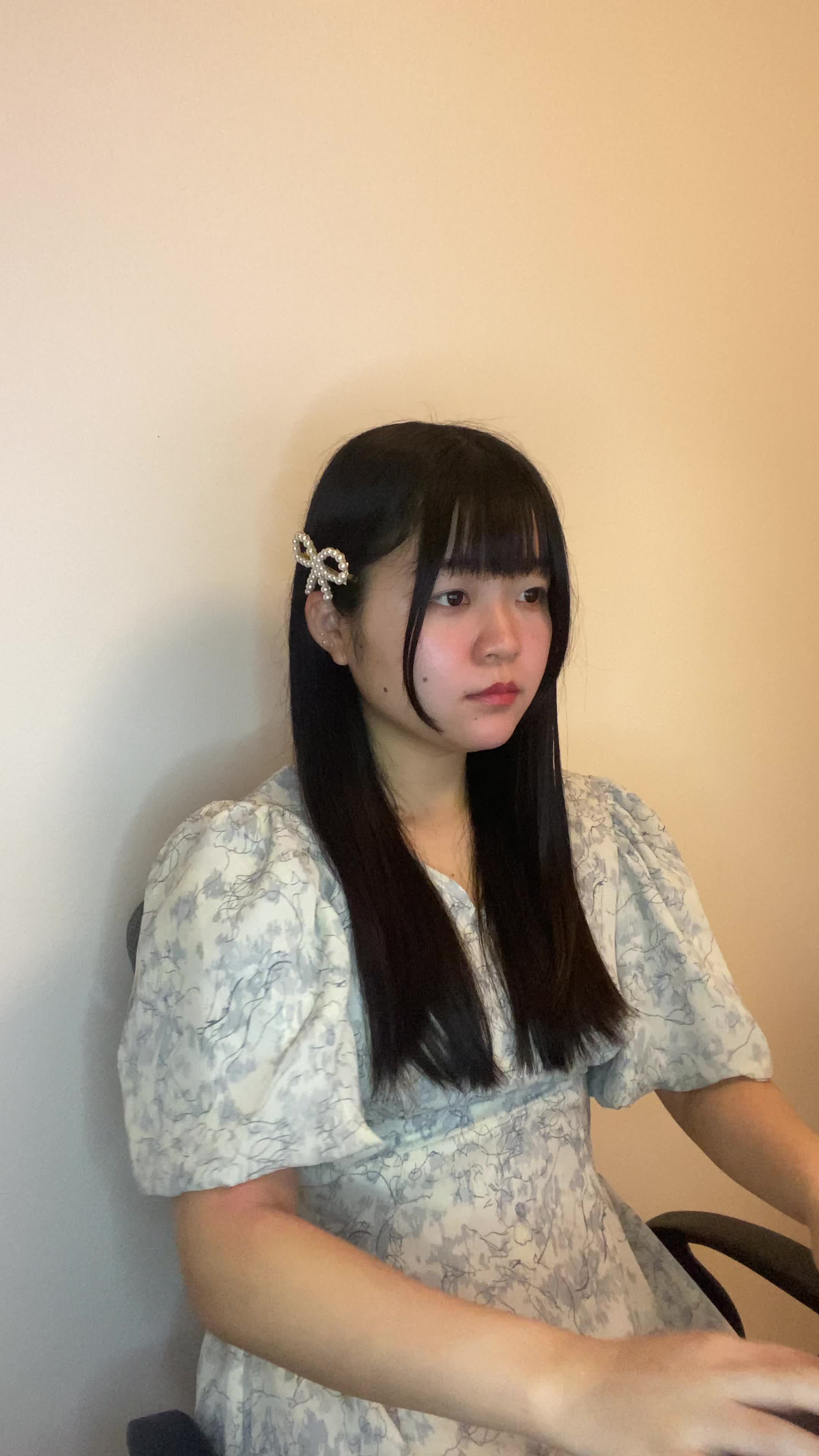 椅子に腰掛け、仕事の合間に鏡を取り出して「やっぱり髪がまとまらない」とため息をつく動作