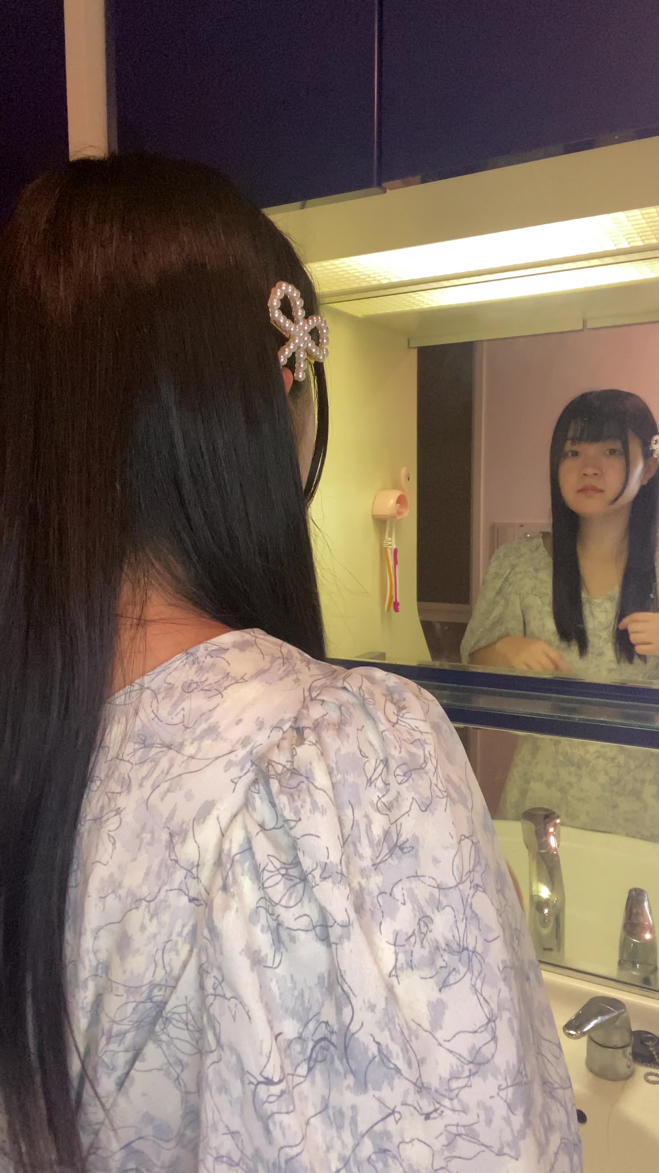 鏡の前で髪を触りながら、「この広がりをどうにかしたい」と悩む姿