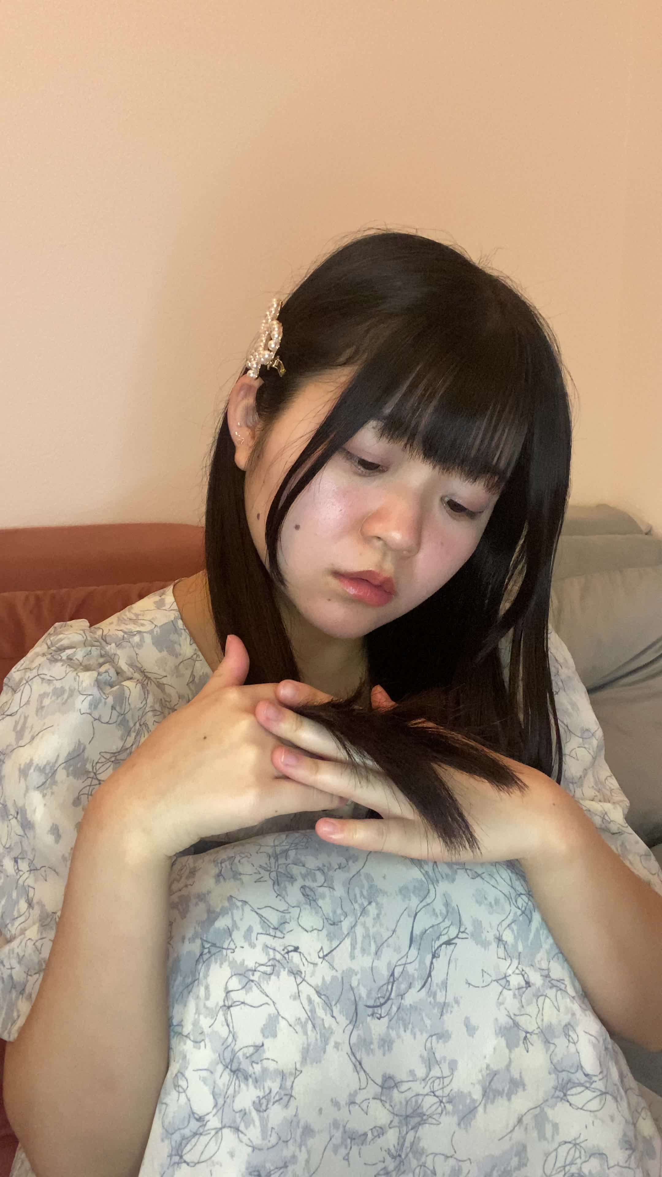 ソファで膝を抱え、「次の週末には髪をツヤツヤにしたい」と考え込む表情
